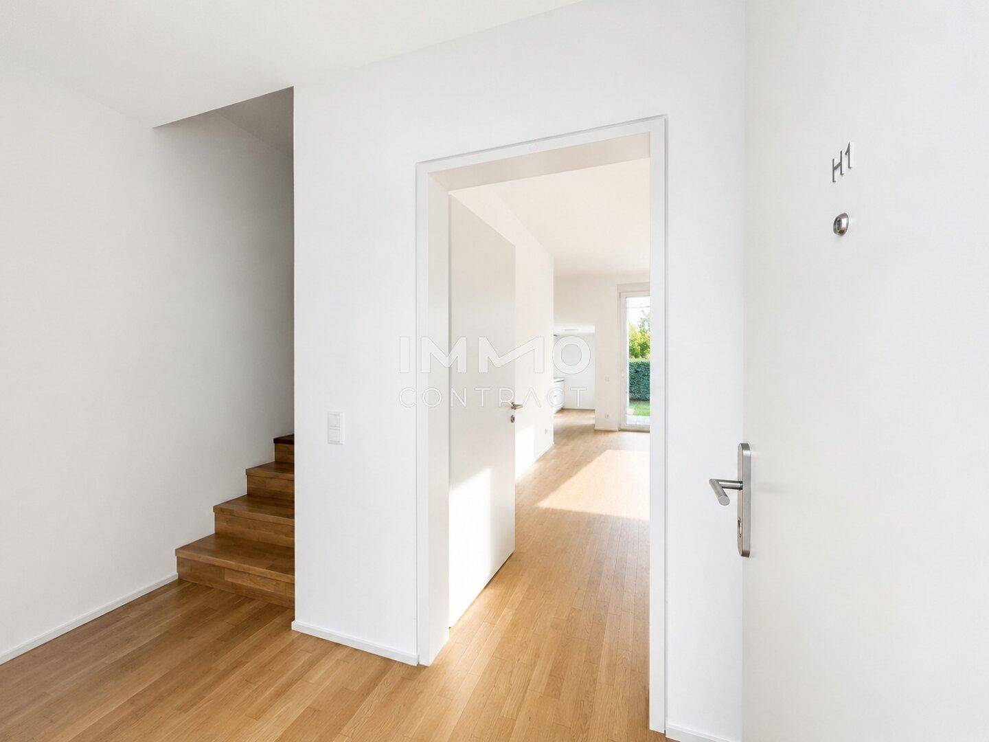 Heller Eingangsbereich mit Holztreppe und Zugang zu den Wohnräumen, einladend und funktional.