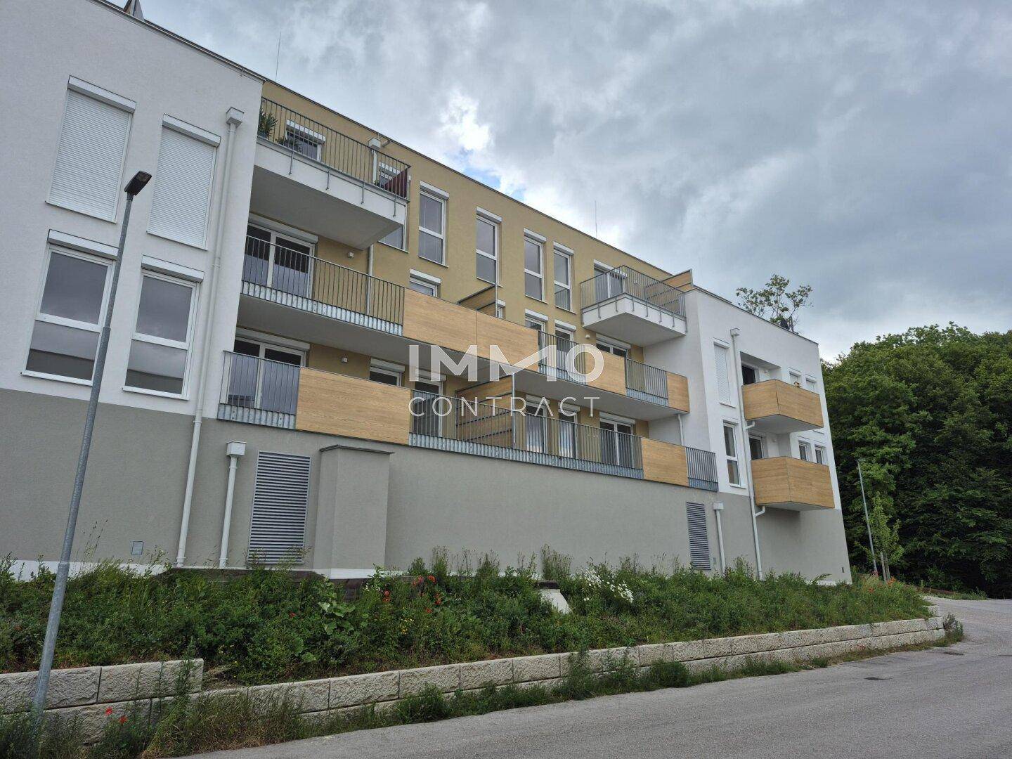 Fassade eines modernen Apartmentgebäudes mit Balkonen und Holzverkleidung.