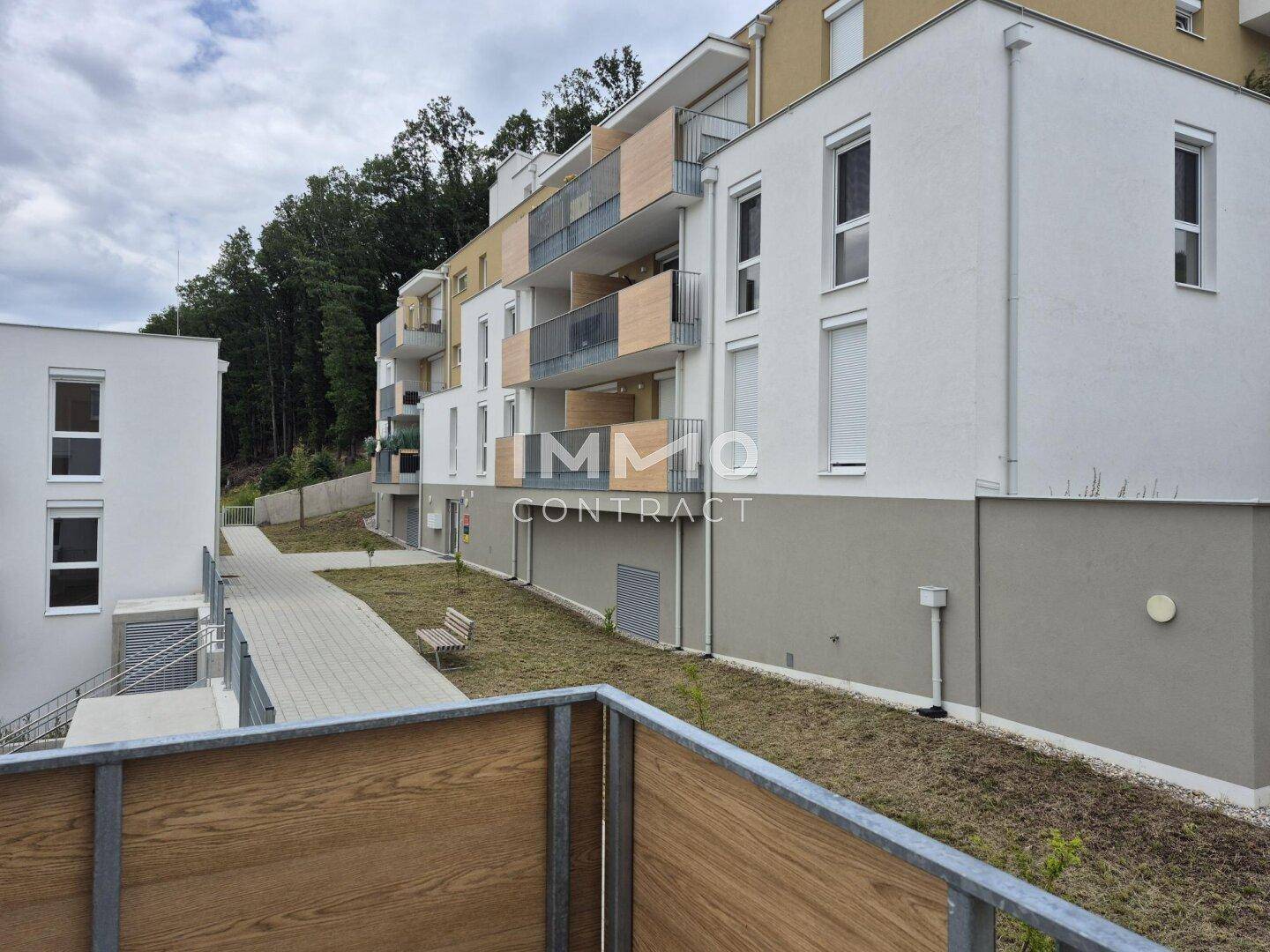 Seitenansicht des Apartmentgebäudes mit Balkonen und Zugangsweg.