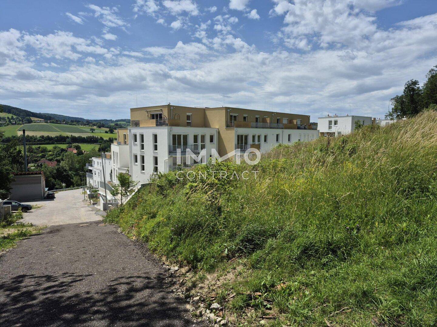 Neubauwohnungen in Hanglage mit weitem Blick über die hügelige Landschaft und grüne Umgebung.