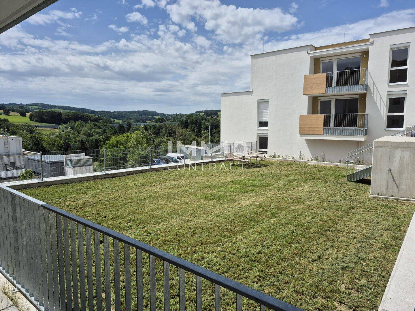 Grüne Dachfläche mit Rasen und Panoramablick auf die umliegende hügelige Landschaft.
