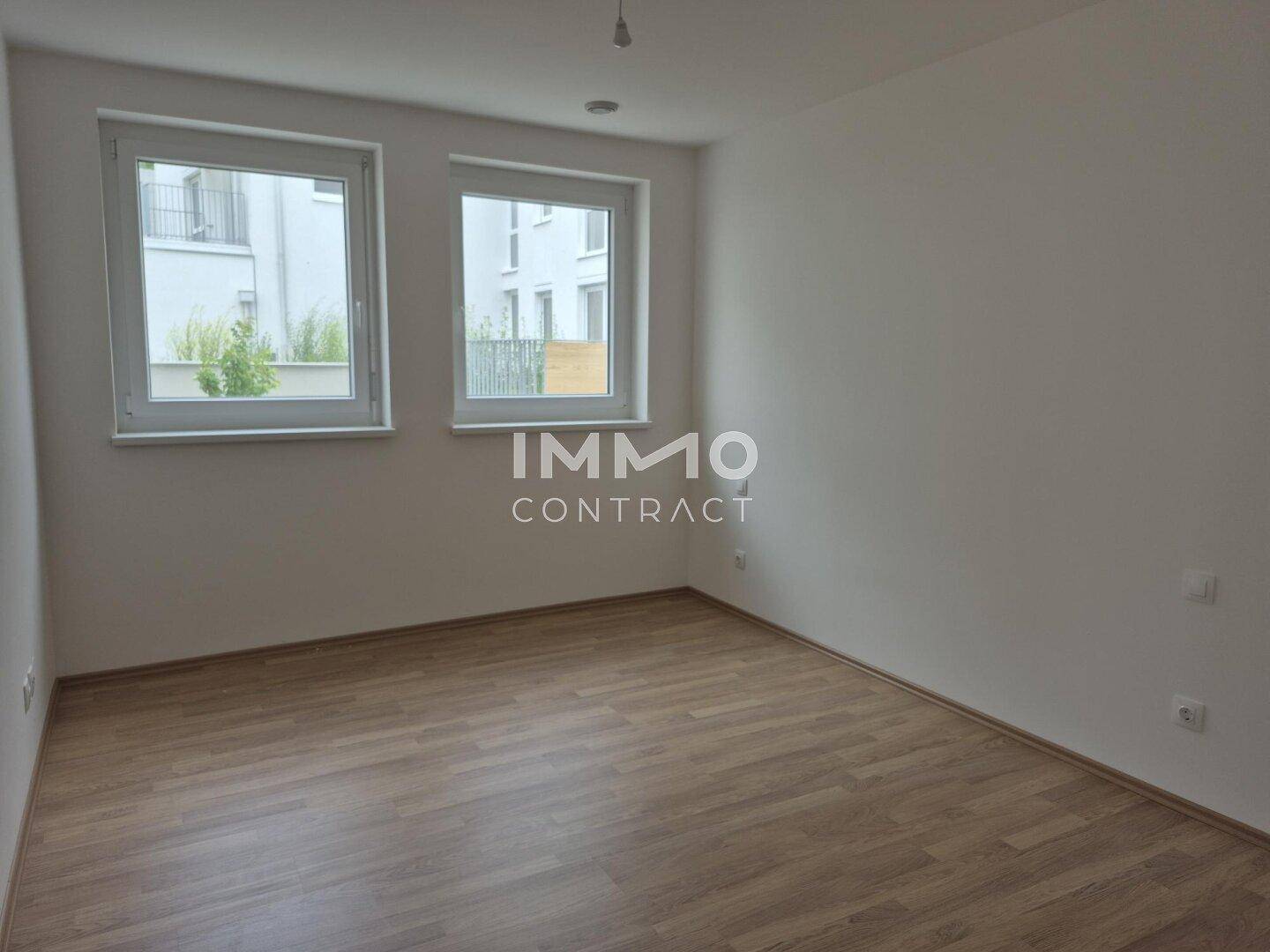 Unmöbliertes Schlafzimmer mit zwei Fenstern und hellem Laminatboden, bietet viel Tageslicht.