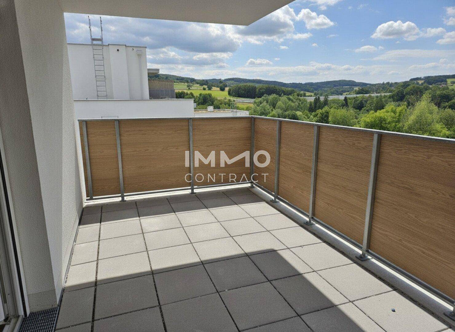 Geräumiger Balkon mit Fliesenboden und weitem Blick ins Grüne.