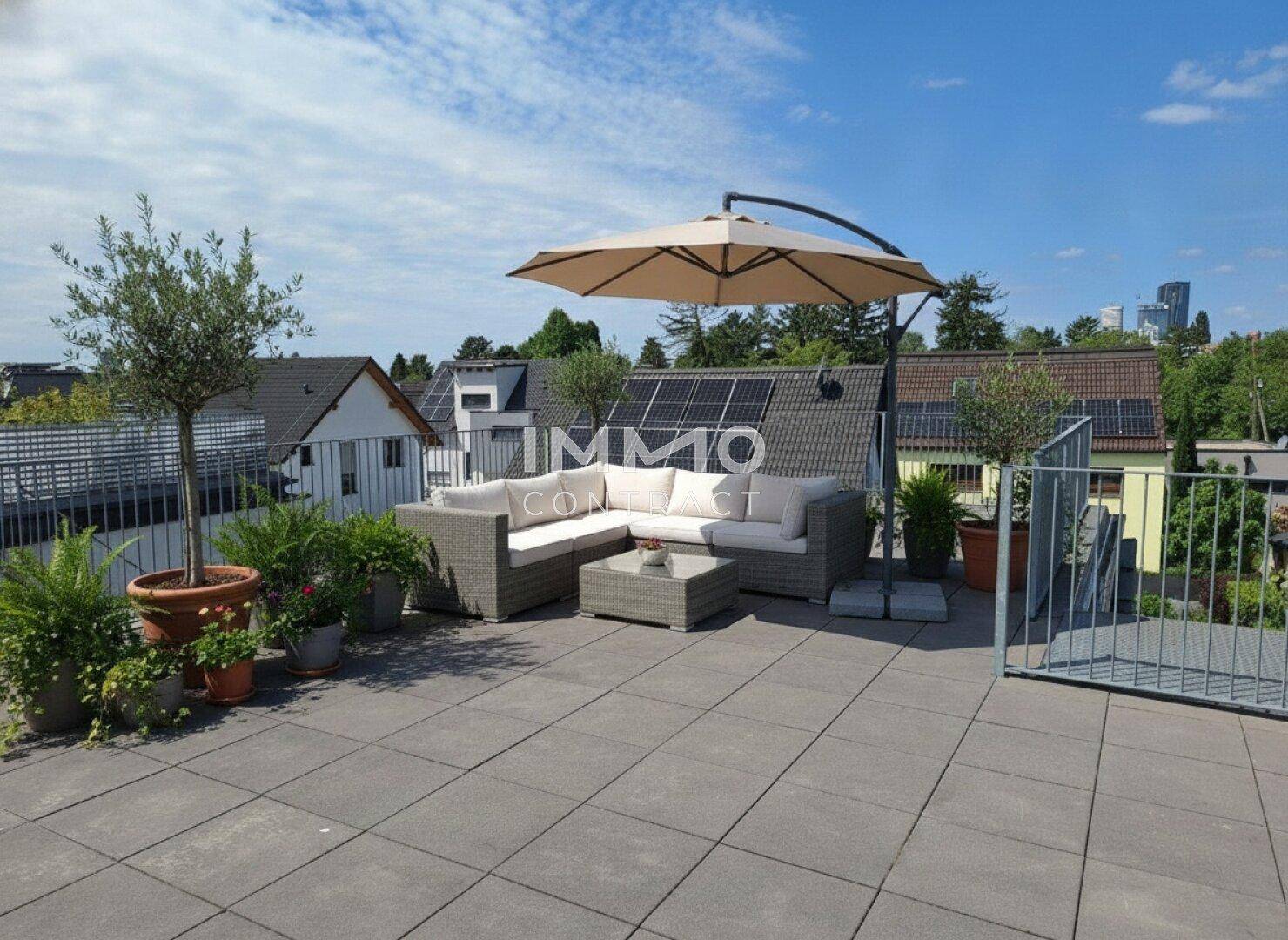 Geräumige Dachterrasse mit Lounge-Möbeln, Sonnenschirm und Blick auf die Umgebung.