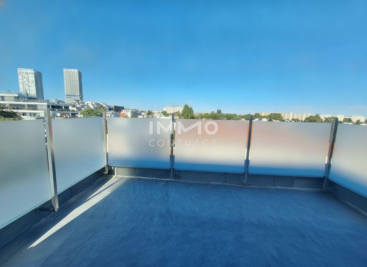 Geräumige Dachterrasse mit Milchglasgeländer und weitem Blick über die Stadt an einem sonnigen Tag.