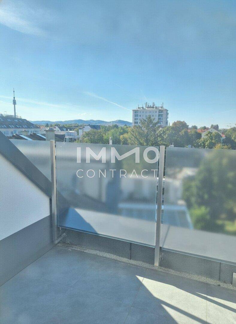 Sonnige Dachterrasse mit modernem Milchglasgeländer und Panoramablick auf die umliegende Stadtlandschaft.