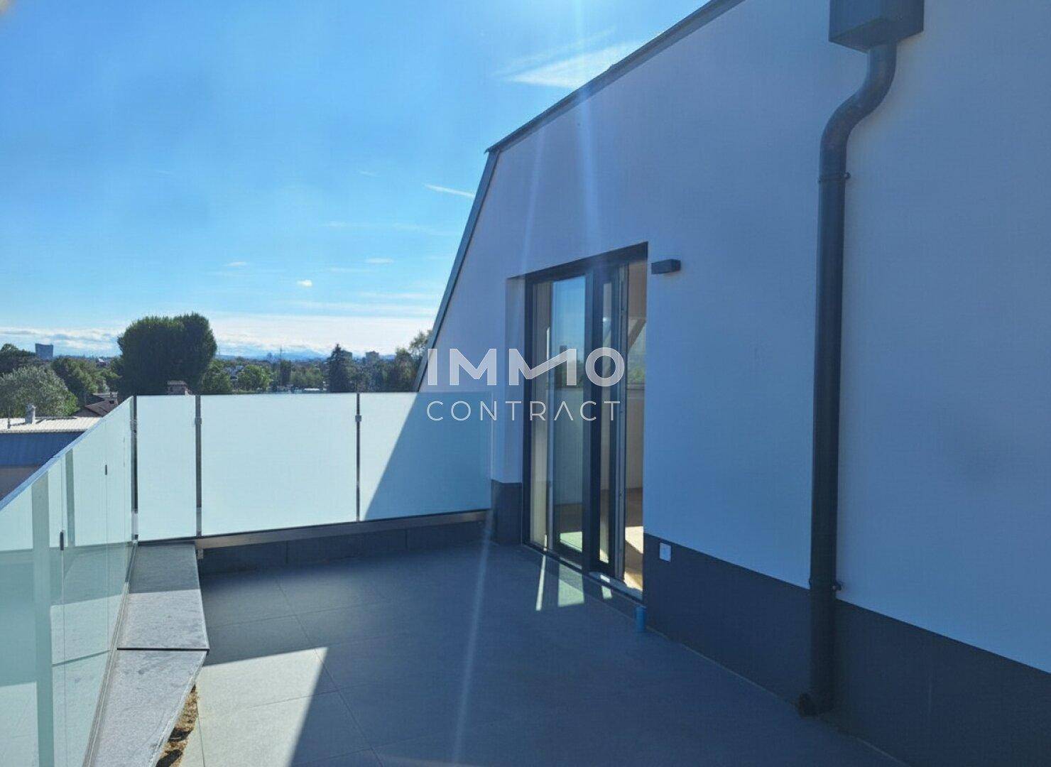 Helle Dachterrasse mit Zugang zum Innenbereich und modernem Glasgeländer unter blauem Himmel.