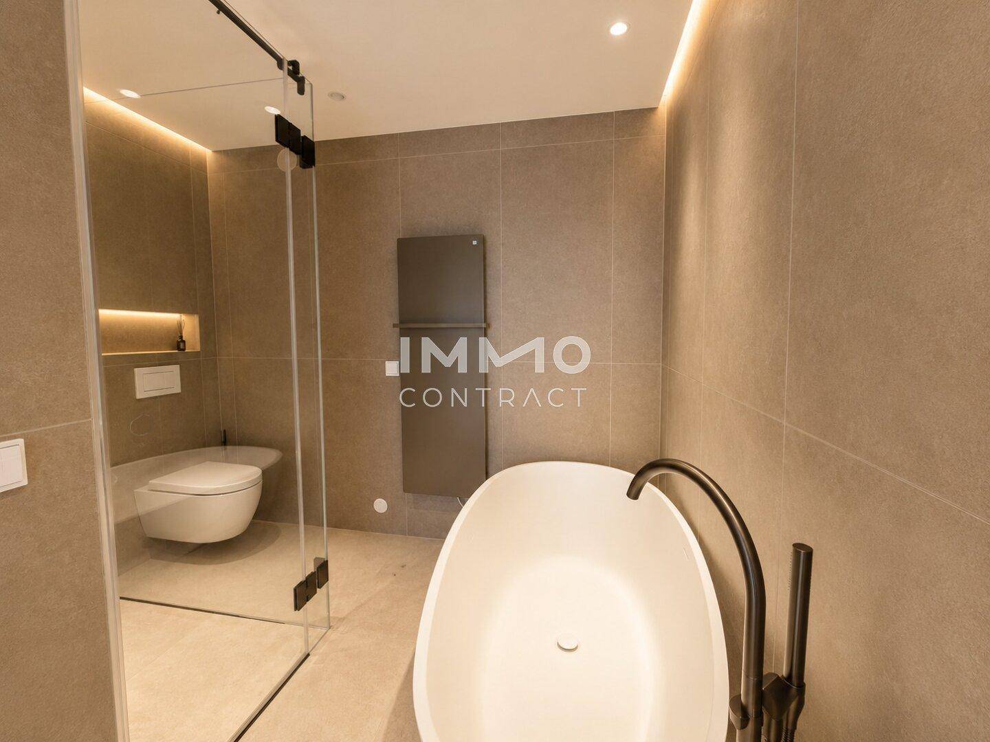 Modernes Badezimmer mit freistehender Badewanne, Wand-WC und eleganten Fliesen.