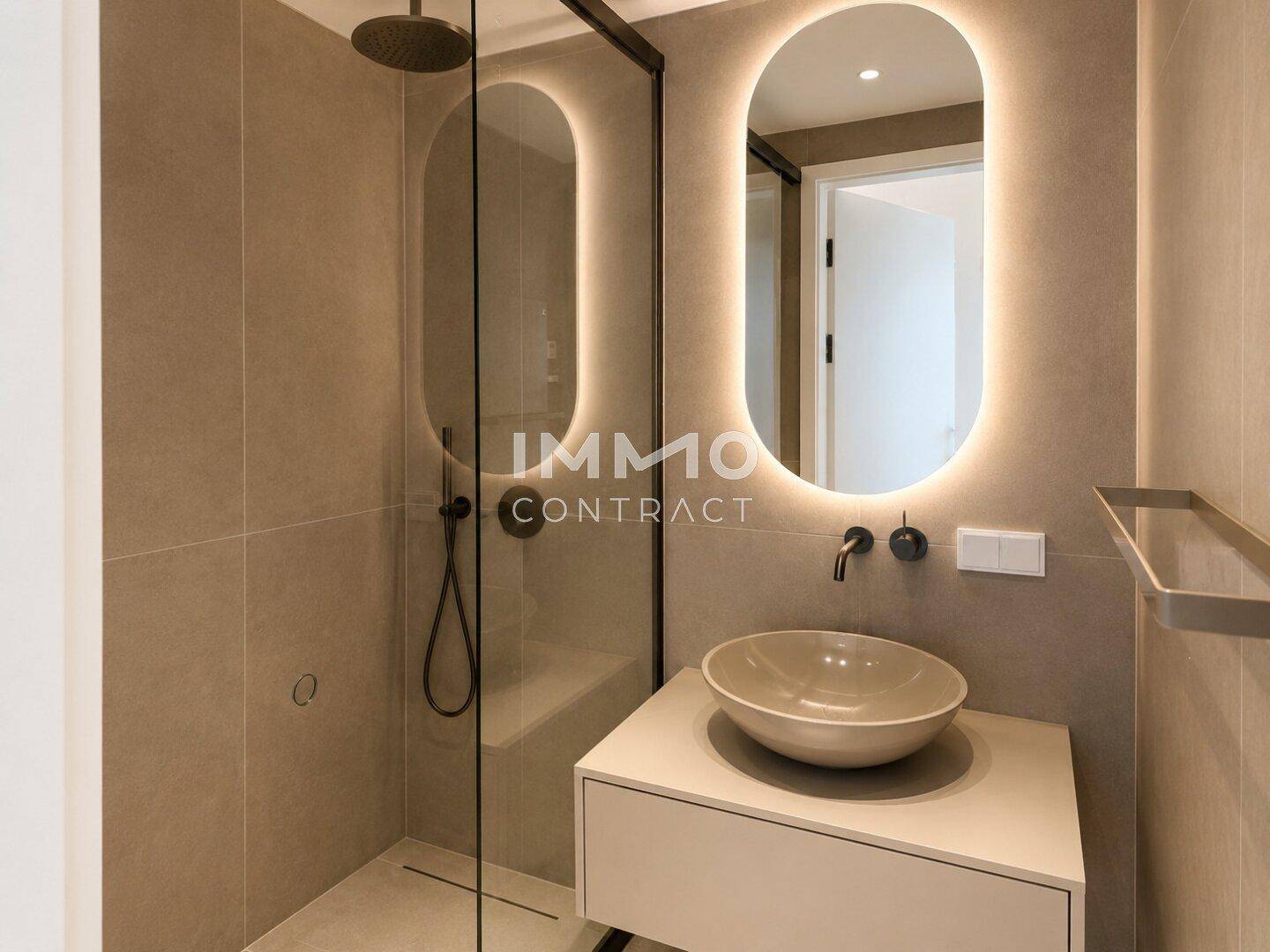 Elegantes Badezimmer mit begehbarer Dusche, modernem Waschbecken und beleuchtetem Spiegel.