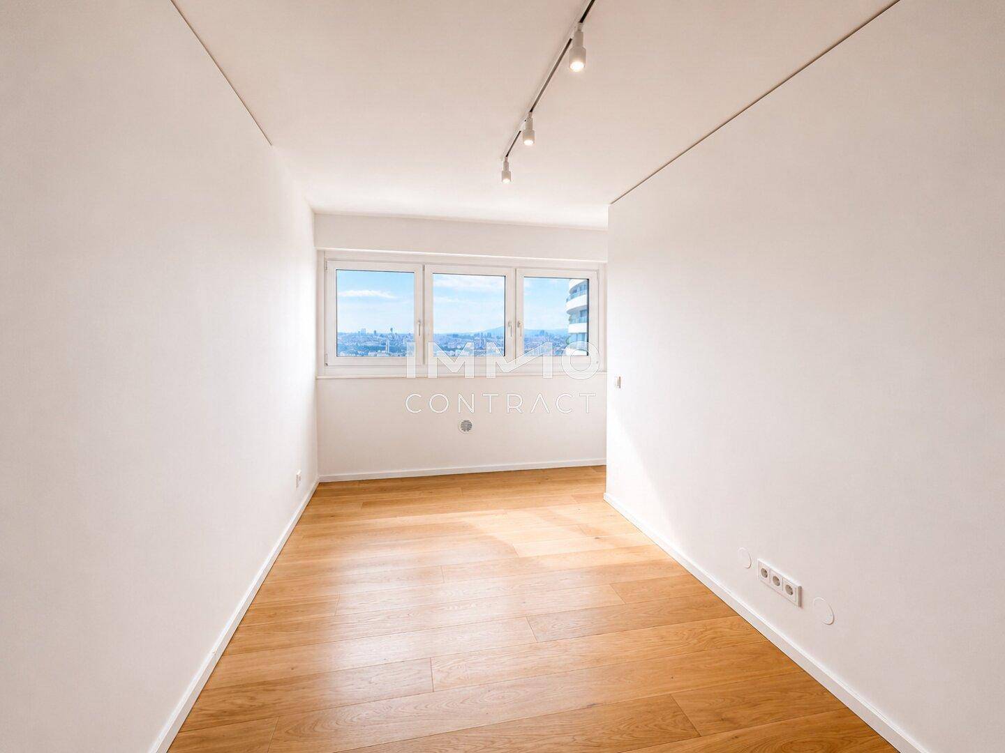 Kleines, helles Zimmer mit Parkettboden und Fenstern, die einen weiten Blick bieten.