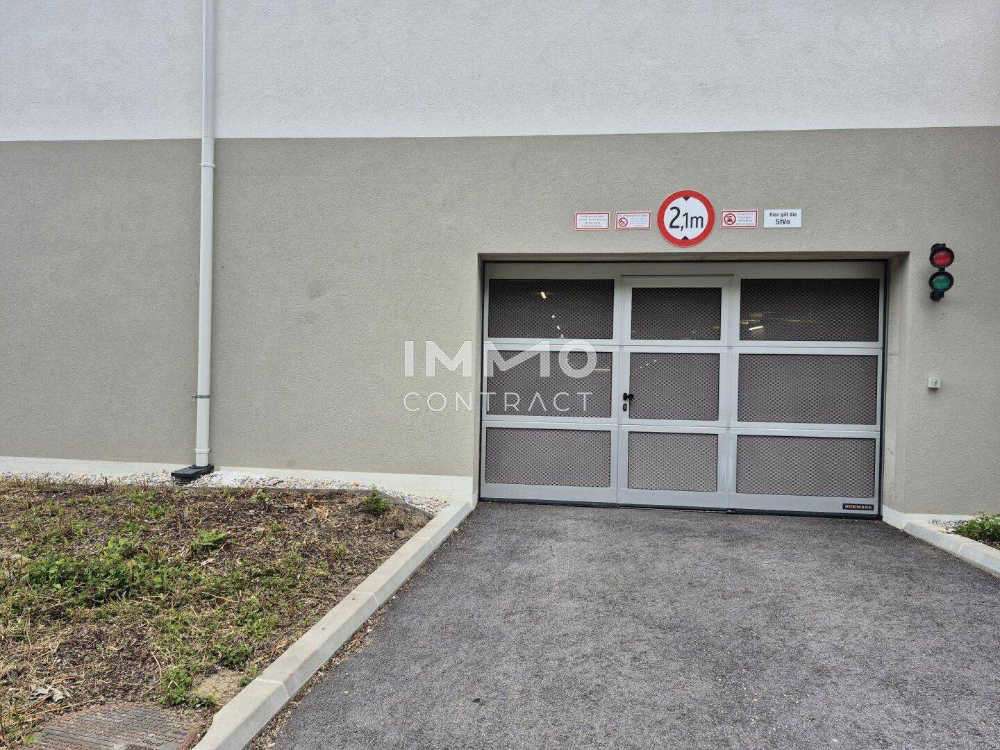 Einfahrt zur Tiefgarage mit Höhenbegrenzung von 2,1 Metern und automatischem Tor.