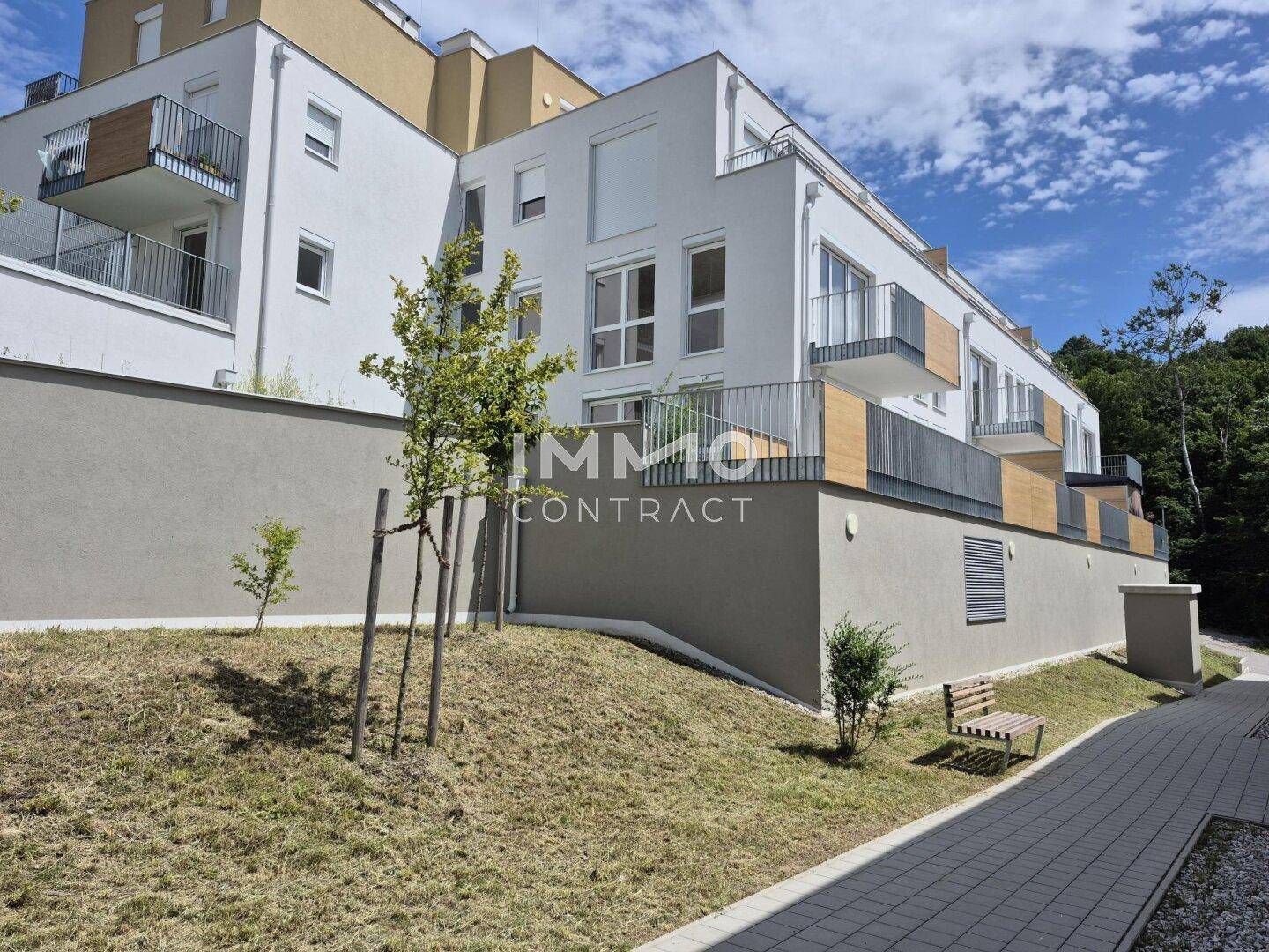 Ansicht des modernen Apartmentgebäudes mit Balkonen und gepflegten Außenanlagen.