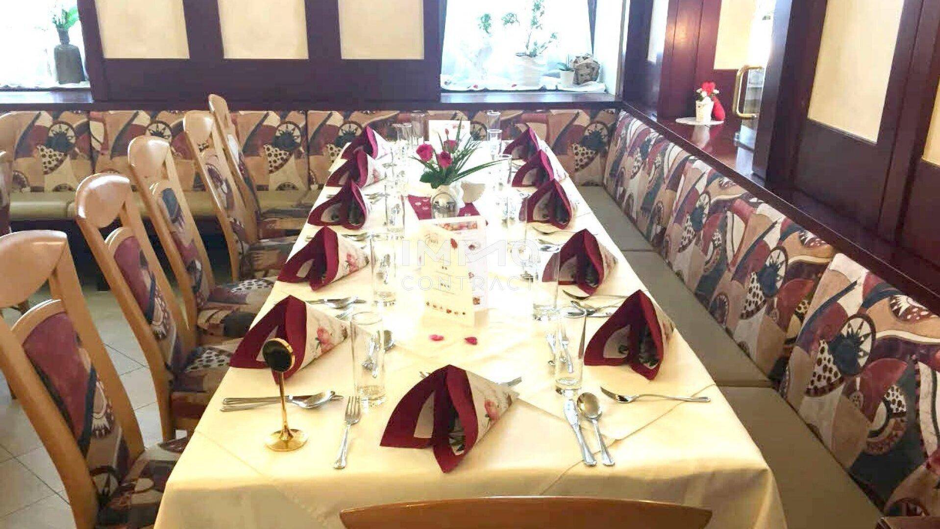 Festlich gedeckter Esstisch in einem traditionellen Restaurantbereich mit gepolsterten Bänken.