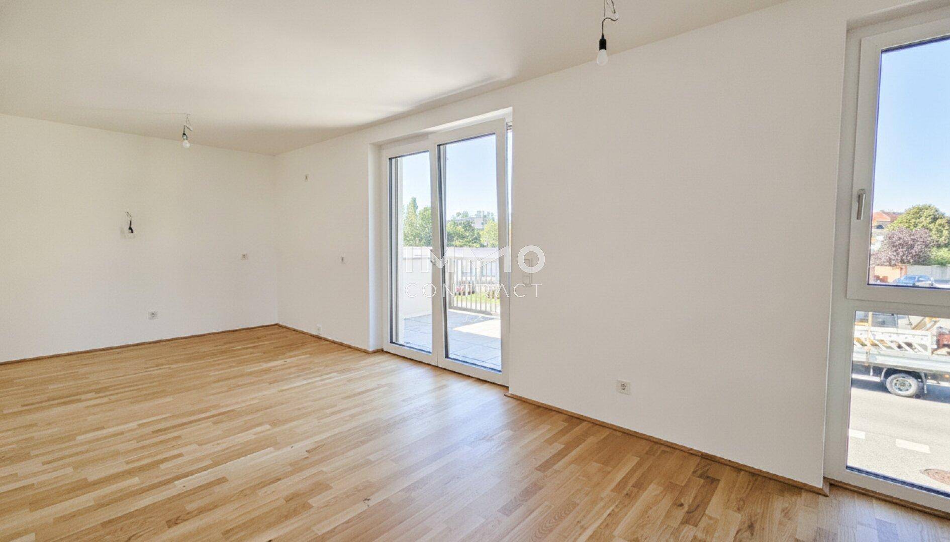 Geräumiger, heller Wohnbereich mit Holzboden und Schiebetür zum Balkon.