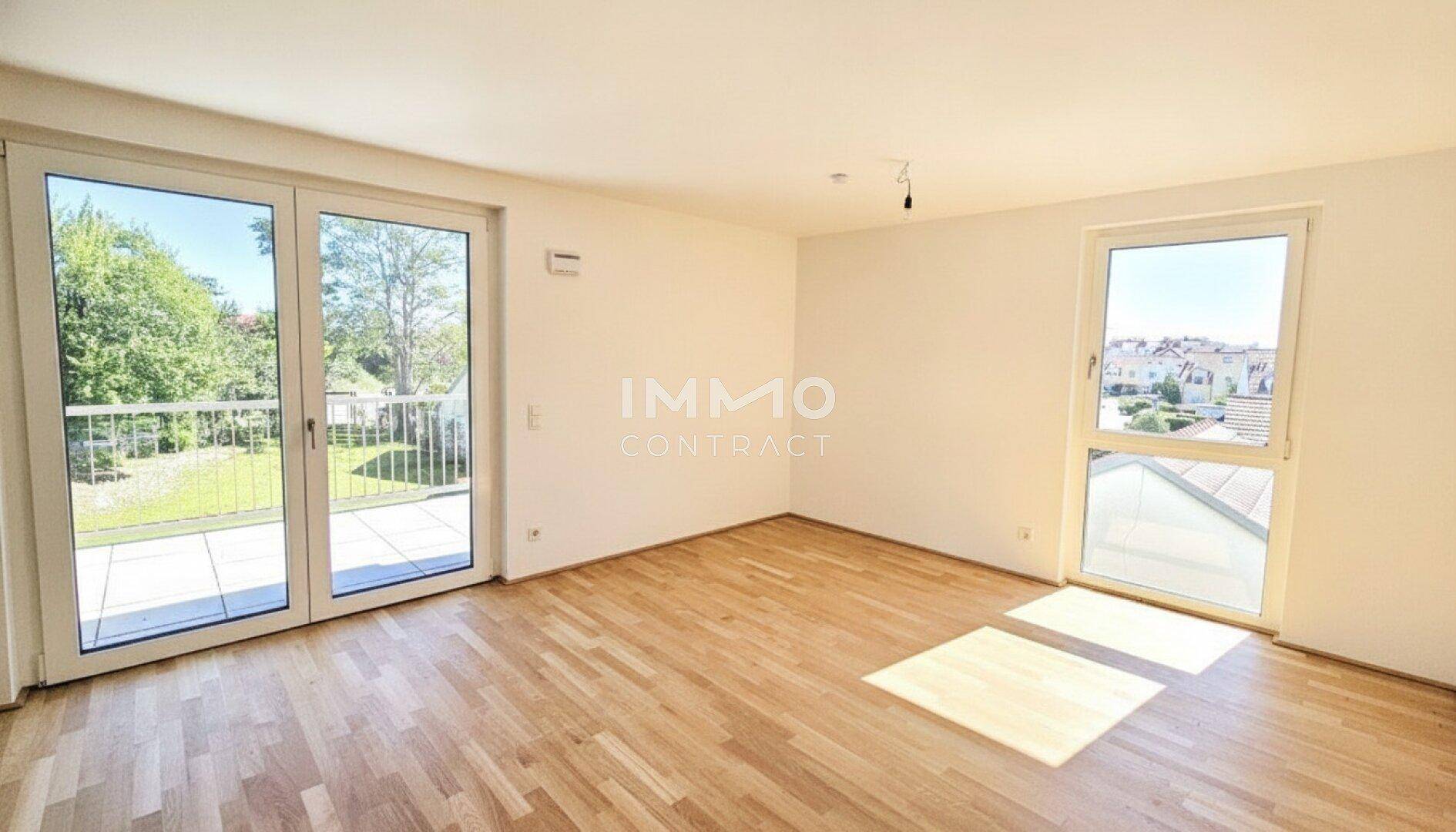 Helles Wohnzimmer mit Parkettboden, großen Fenstern und Zugang zu einer Terrasse.