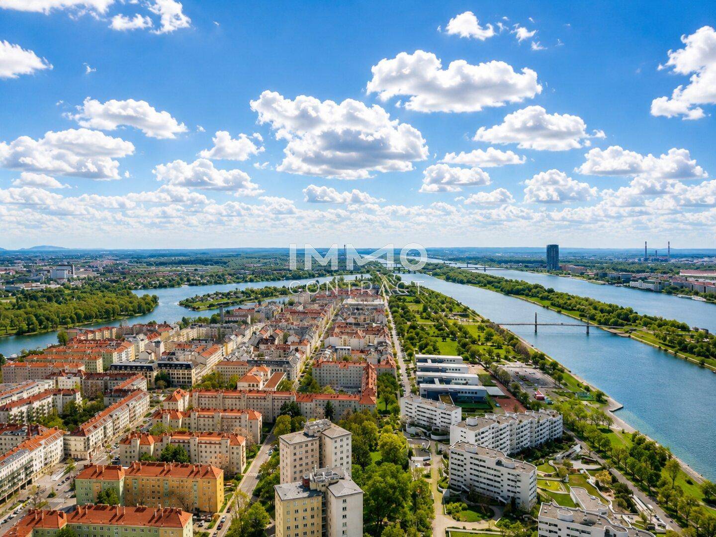 Panoramablick aus der Vogelperspektive auf eine weitläufige Stadtlandschaft mit Fluss und Brücken.