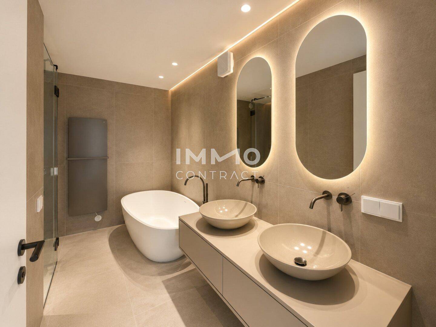 Elegantes Badezimmer mit Doppelwaschbecken, freistehender Badewanne und beleuchteten Spiegeln.