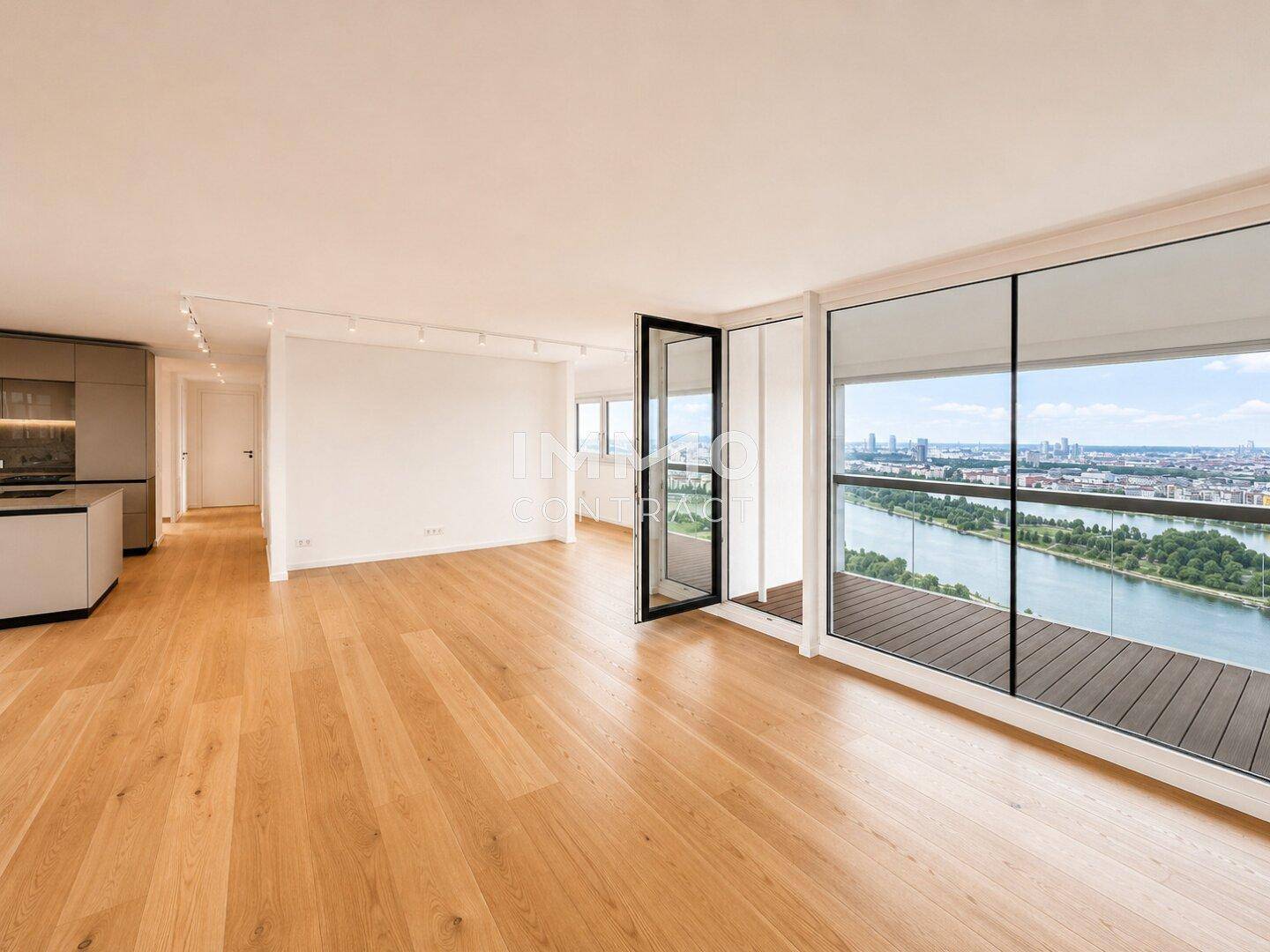 Offener Wohnbereich mit Holzboden und Zugang zu einem Balkon mit Flussblick.