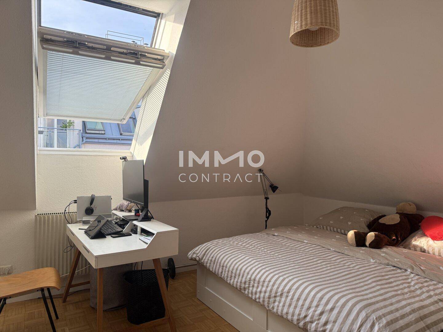 Schlafzimmer mit Arbeitsplatz, Dachschräge und großem Dachfenster, das viel Licht hereinlässt.