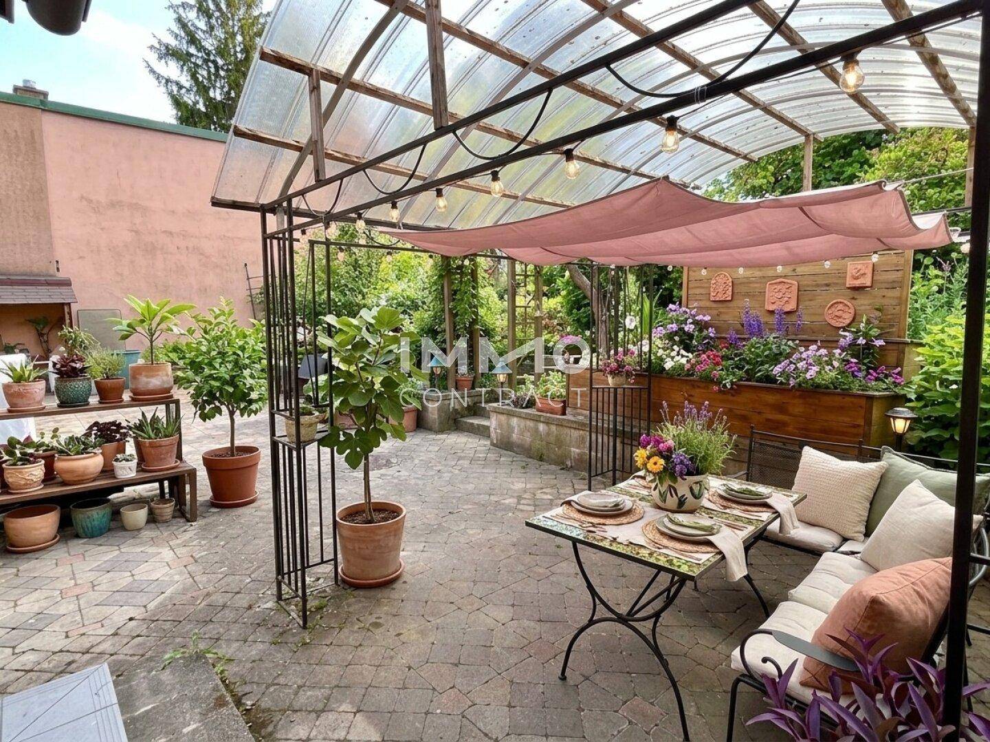 Gemütliche überdachte Terrasse mit Esstisch, vielen Pflanzen und dekorativer Beleuchtung für entspannte Stunden.