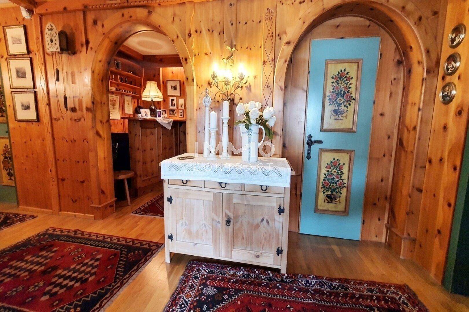 Rustikaler Eingangsbereich mit Holztäfelung, handbemalter Tür und traditionellen Teppichen.