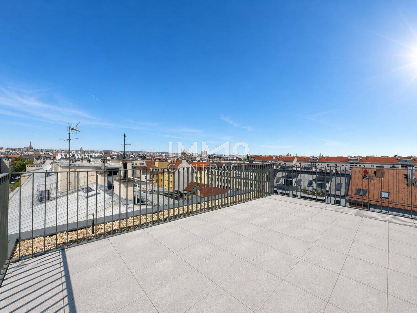 Weitläufige Dachterrasse mit Fliesenboden und Panoramablick über die Stadt.