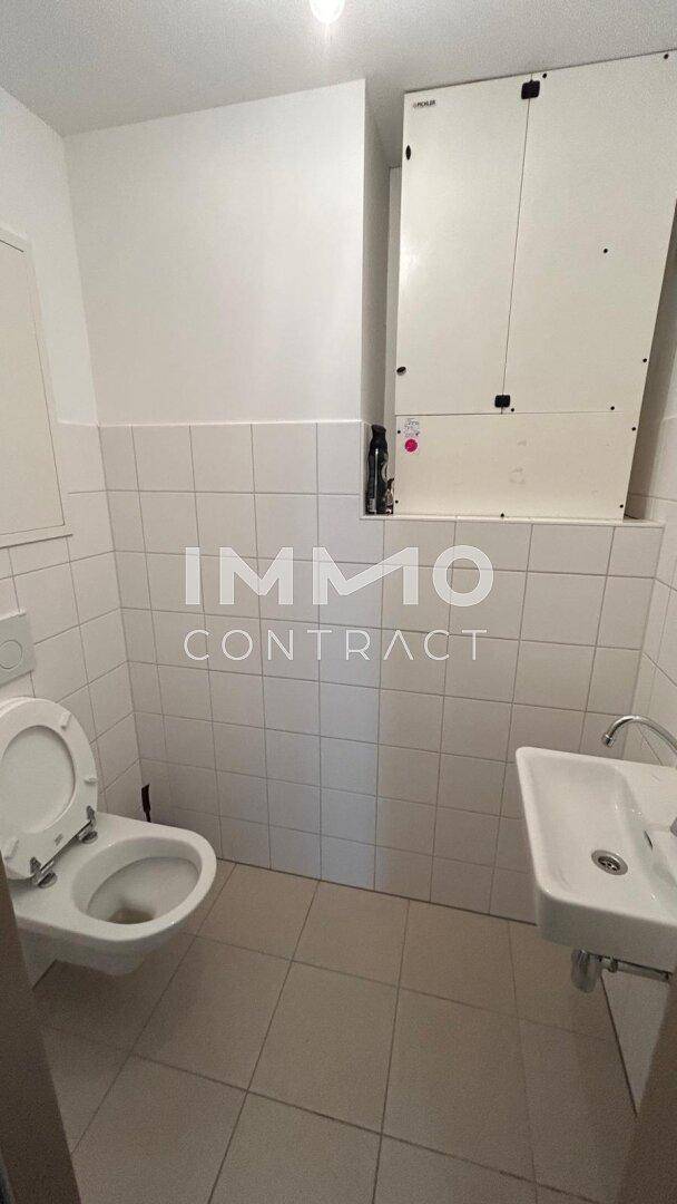 Kleines Gäste-WC mit Wand-WC, Waschbecken und weißen Fliesen.