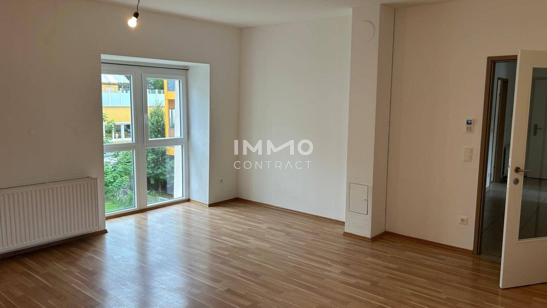 Geräumiges Wohnzimmer mit Parkettboden, großen Fenstern und Blick ins Grüne.