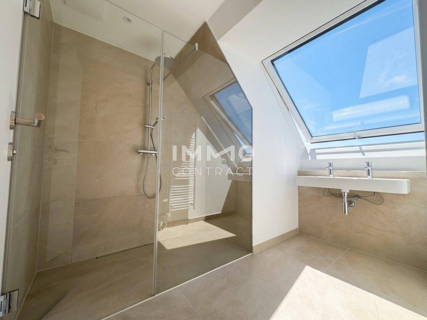Modernes Badezimmer mit begehbarer Dusche, Dachfenster und hellen Fliesen.