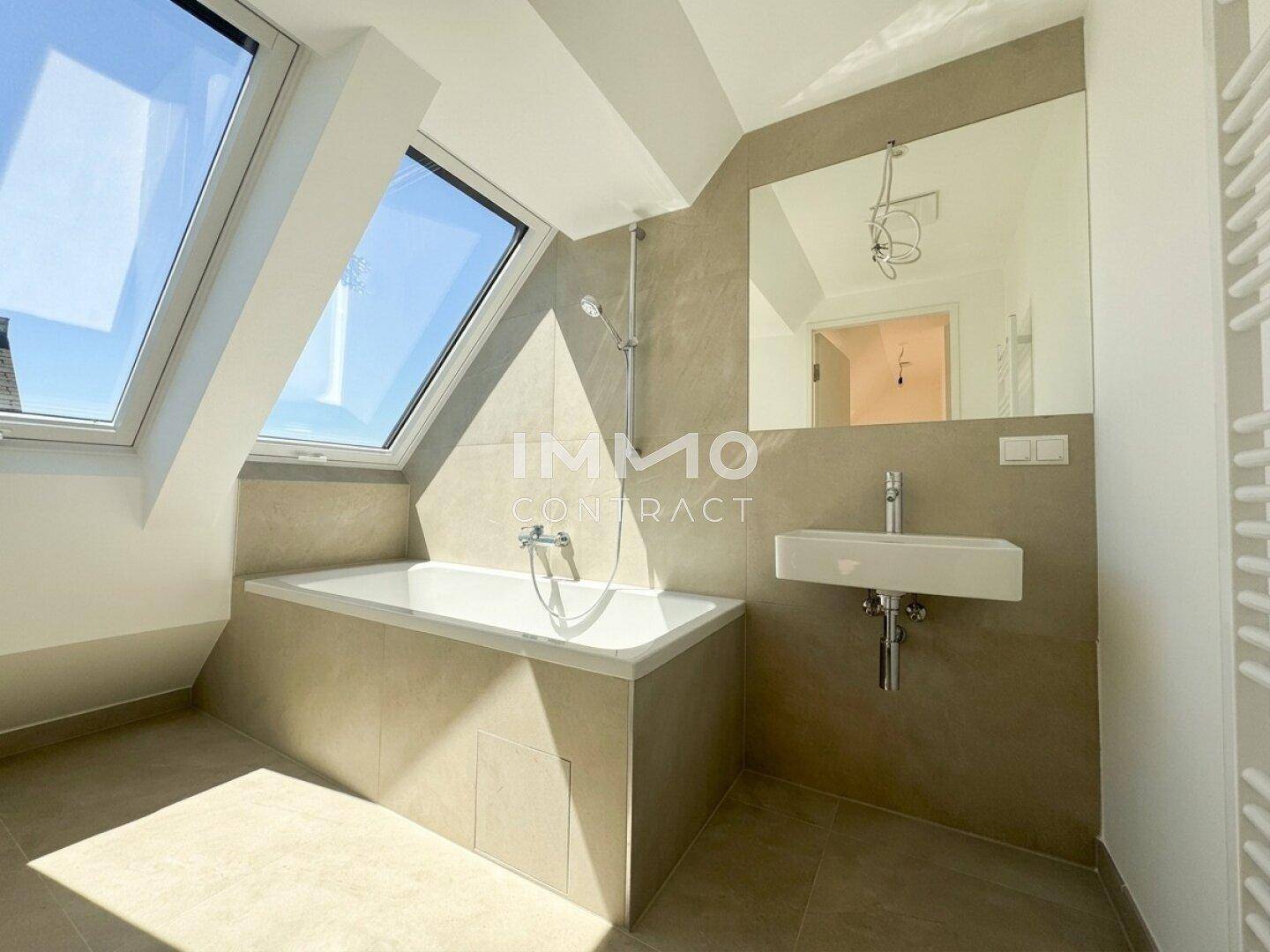 Modernes Badezimmer mit Badewanne, Dachfenster und großem Spiegel über dem Waschbecken.