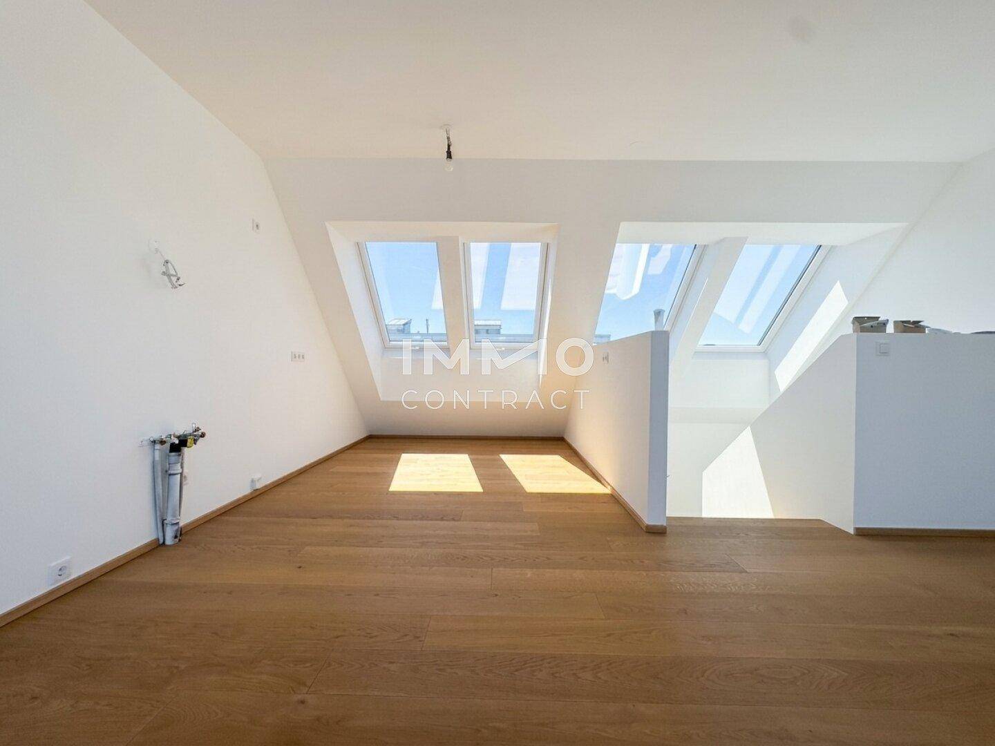 Heller Wohnbereich mit Holzboden und großen Dachfenstern, die viel Tageslicht hereinlassen.