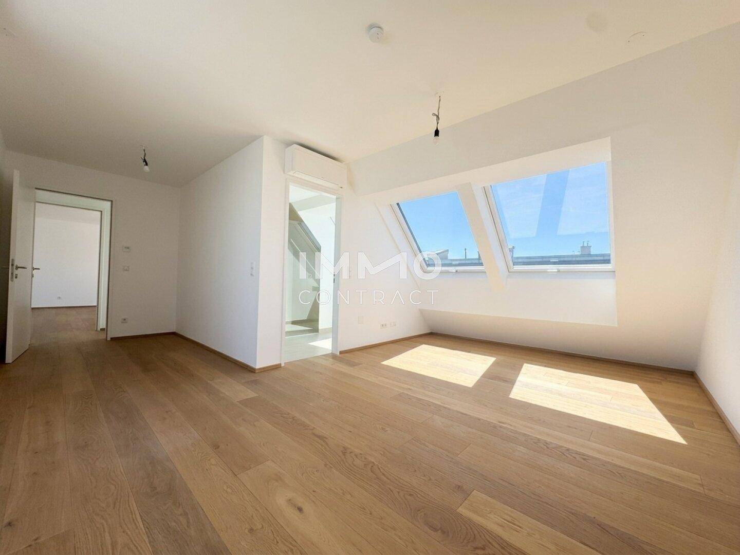 Lichtdurchfluteter Raum mit Holzboden, Dachfenstern und Klimaanlage, ideal als Wohnbereich.