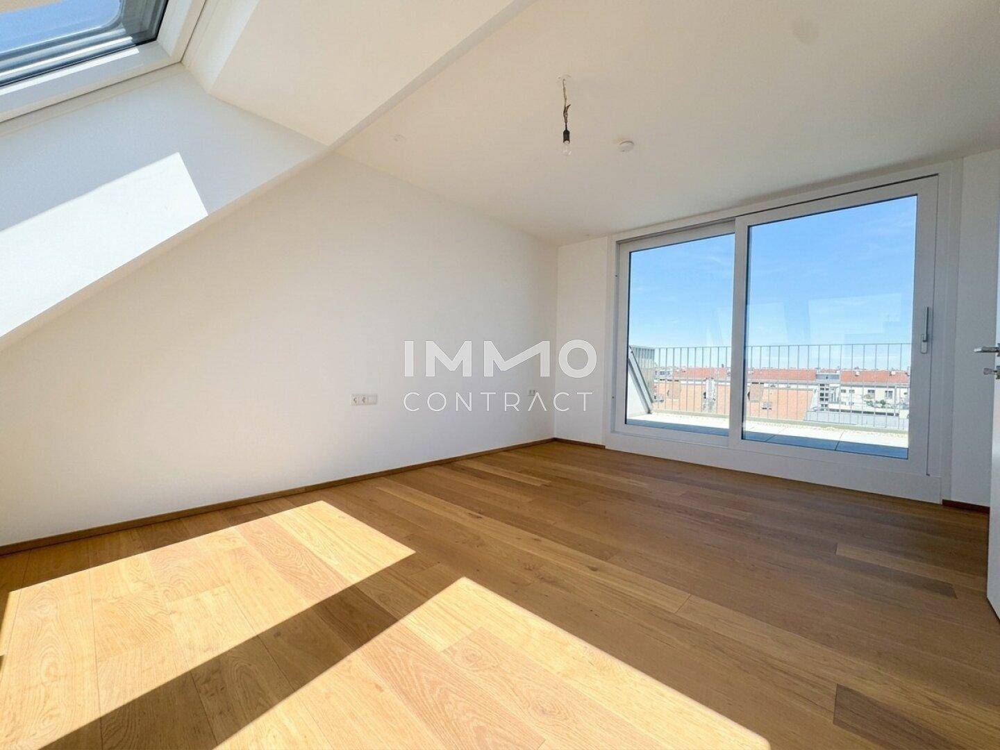 Helles Zimmer mit Holzboden, Dachschräge und großem Fenster mit Stadtblick.