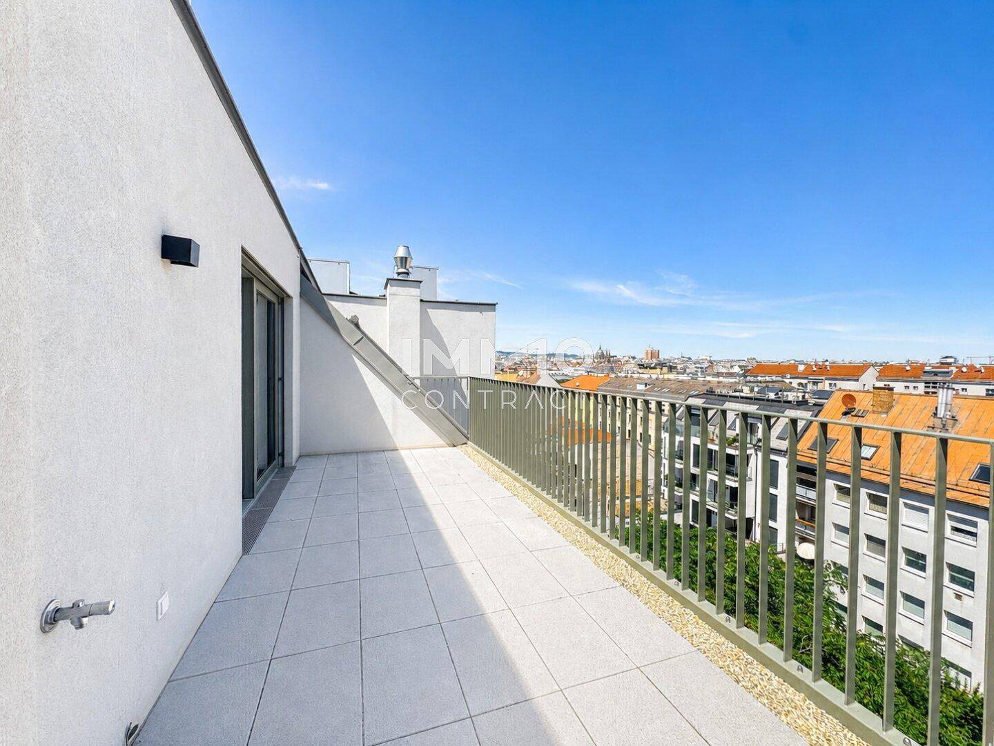 Geräumige Dachterrasse mit Fliesenboden und Metallgeländer, bietet weiten Stadtblick.