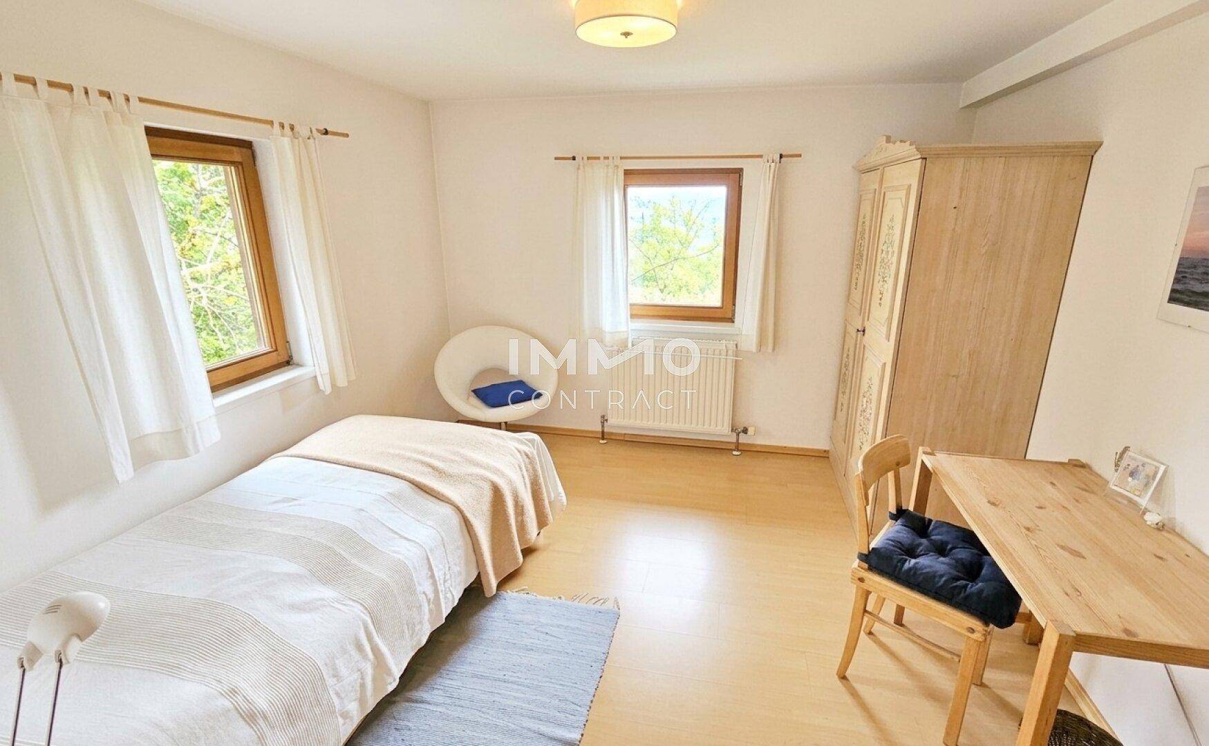 Gemütliches Schlafzimmer mit Einzelbett, Holzmöbeln und Blick ins Grüne.
