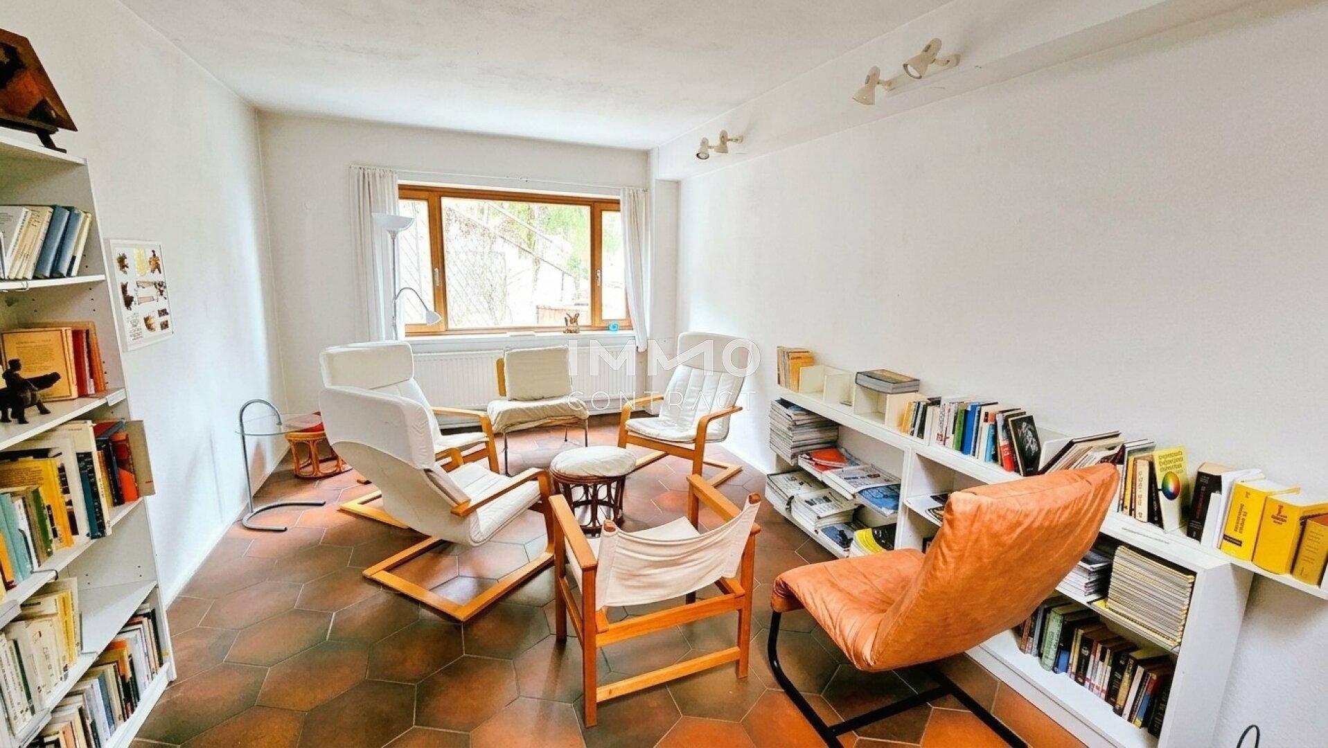 Wohnzimmer mit zahlreichen Bücherregalen und bequemen Sesseln, ideal zum Entspannen.