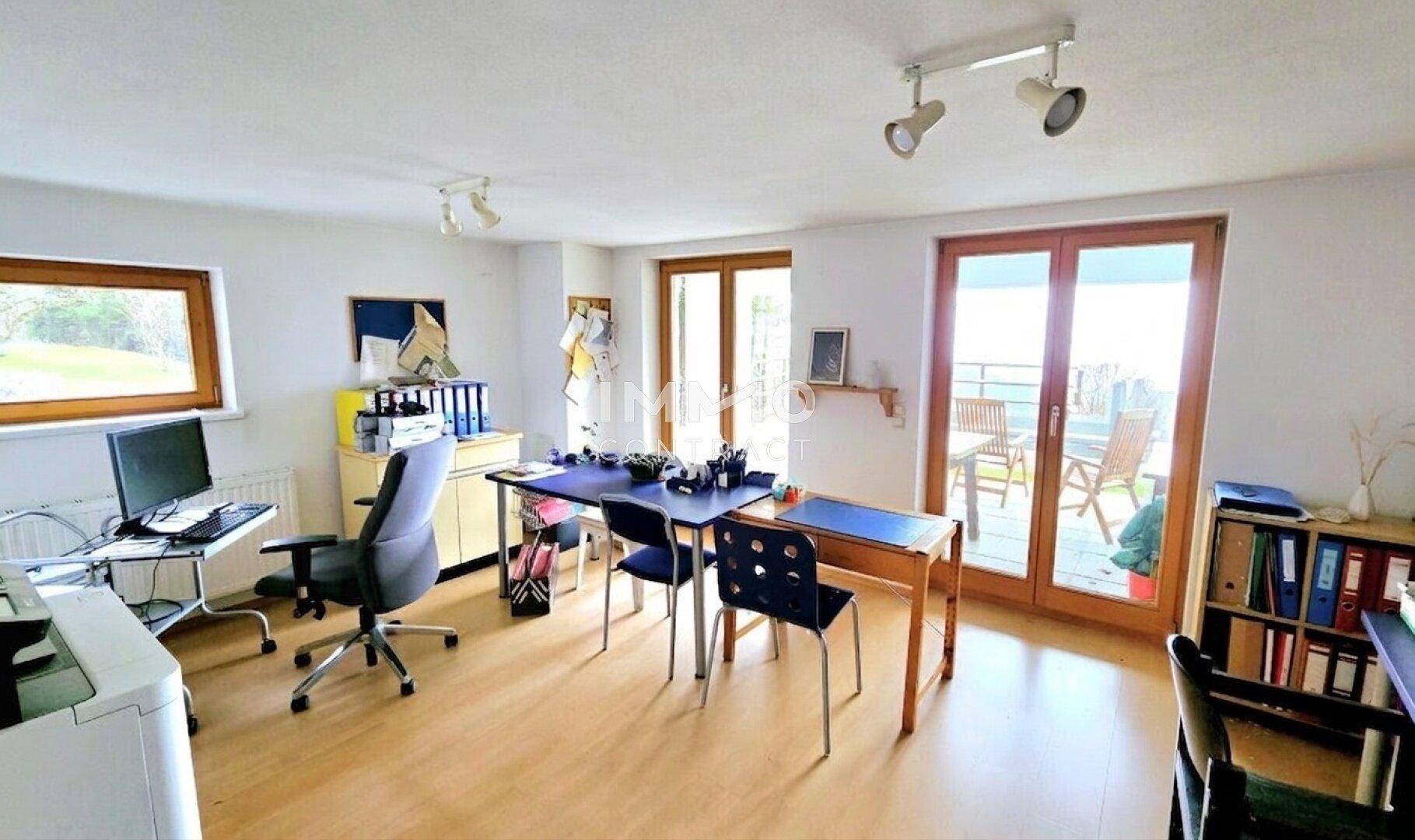 Funktional eingerichtetes Büro mit viel Tageslicht und direktem Zugang zum Balkon.