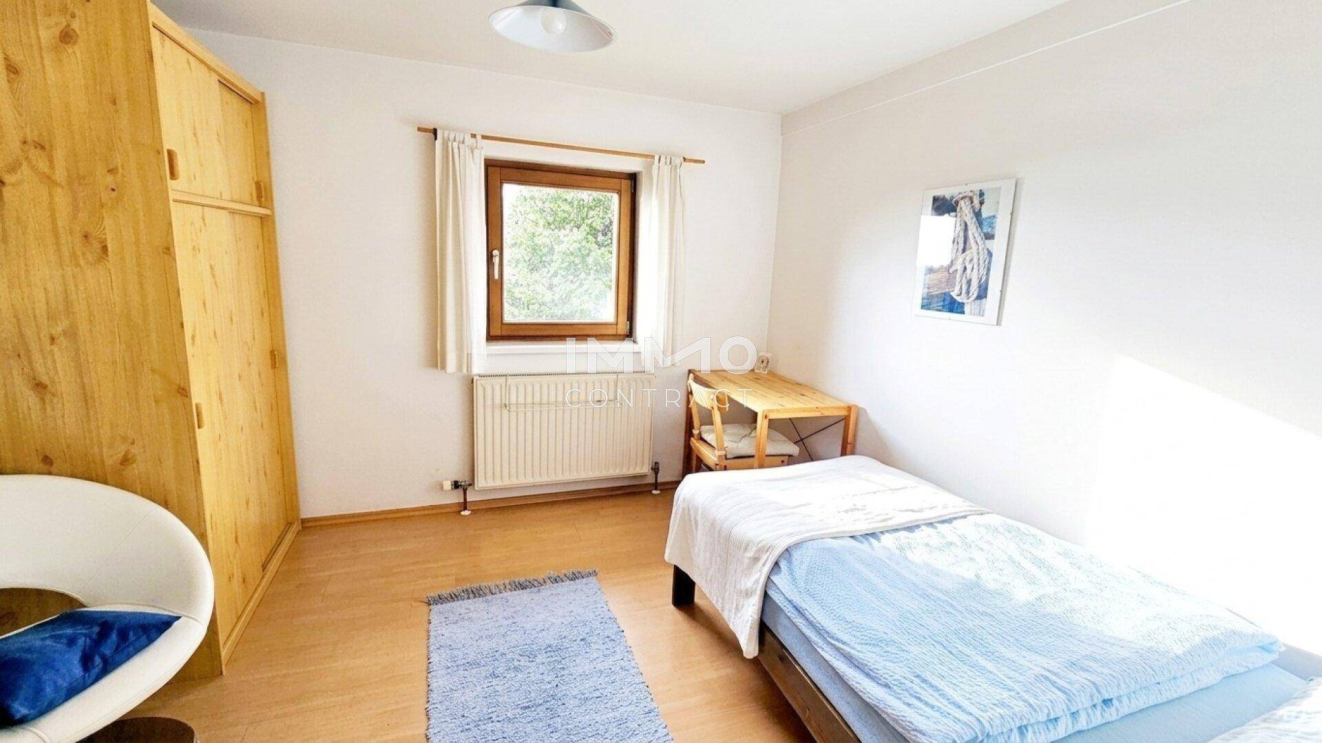 Einfaches Schlafzimmer mit Einzelbett, Holzschrank und Laminatboden.