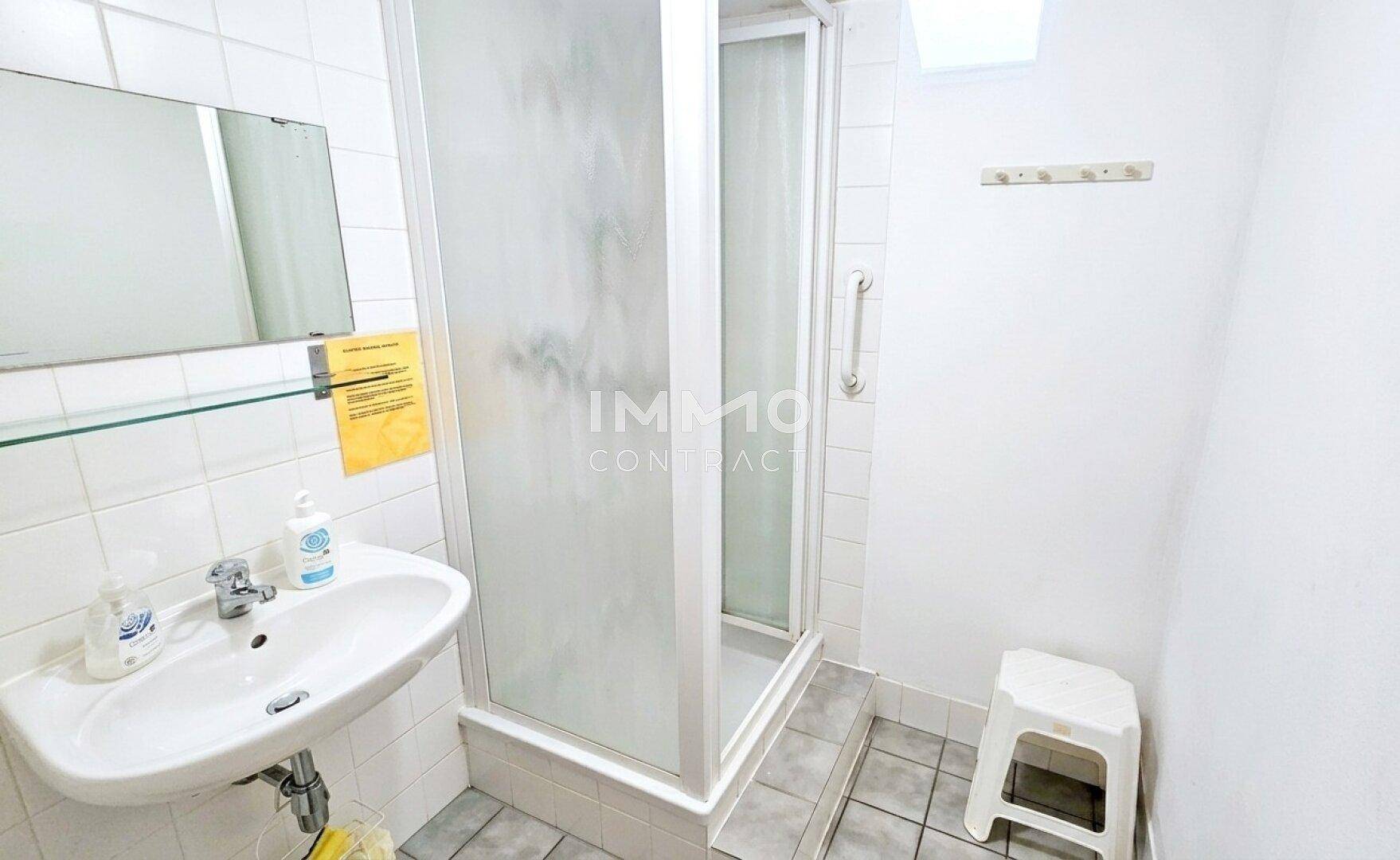 Helles Badezimmer mit Dusche, Waschbecken und Fliesenboden.