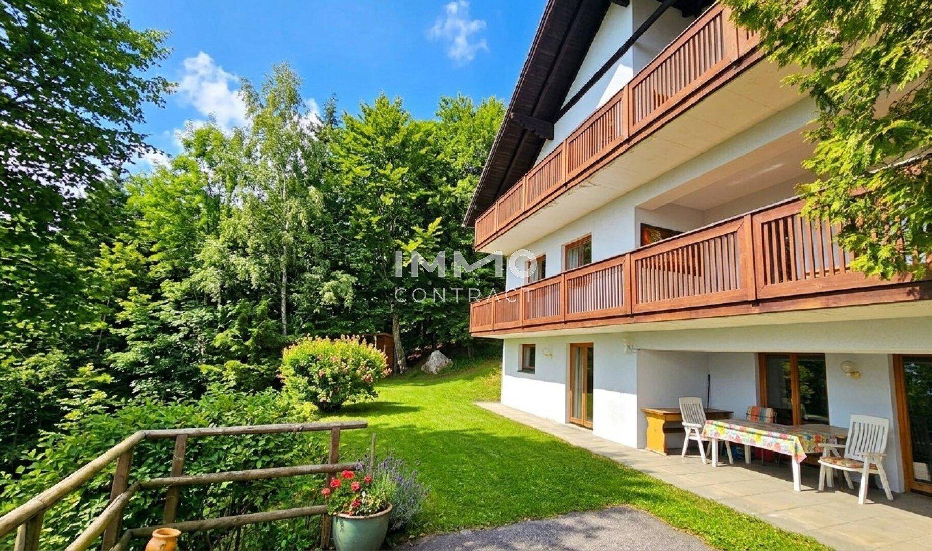 Sonniger Außenbereich mit Terrasse und mehreren Balkonen, umgeben von üppigem Grün.