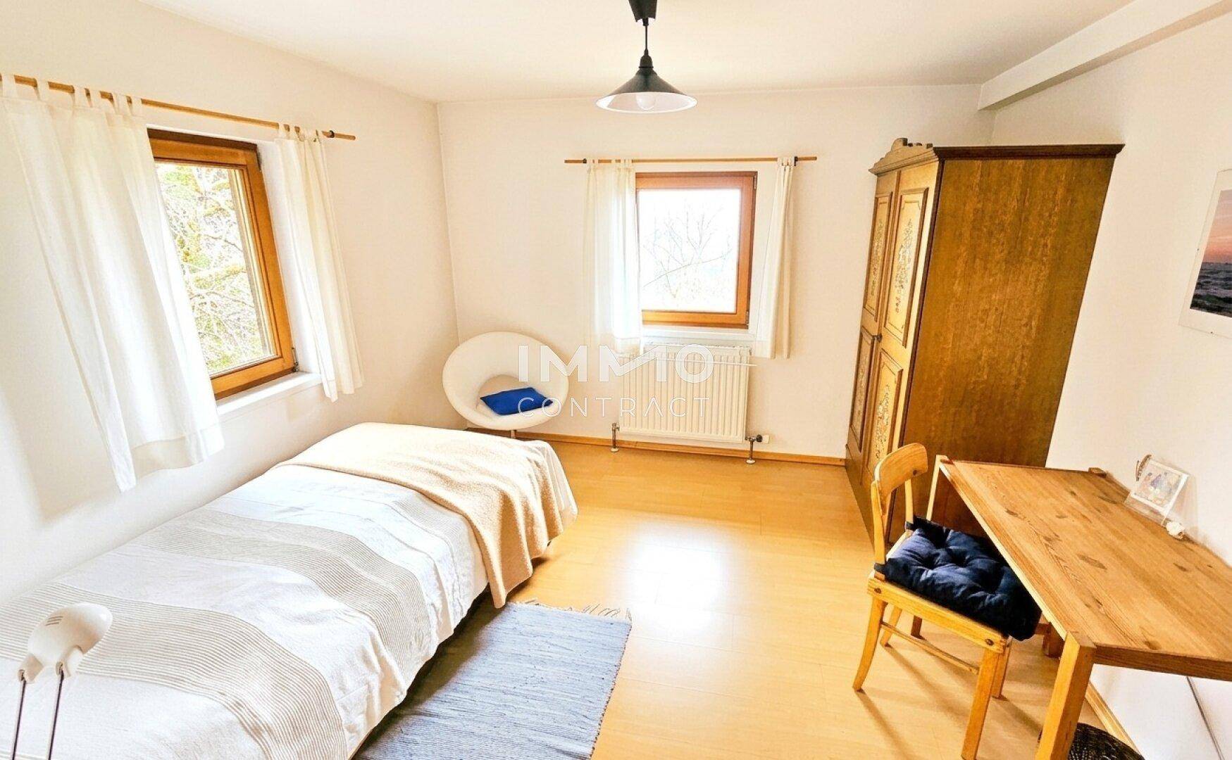 Einfaches Schlafzimmer mit Einzelbett, Holzschrank und hellem Laminatboden.