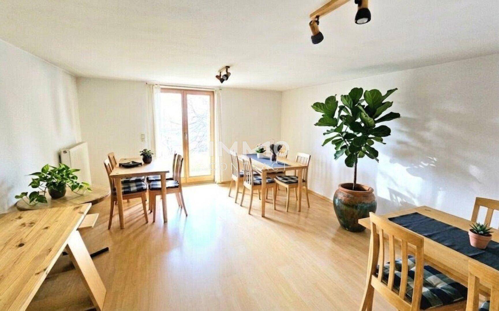 Heller Essbereich mit mehreren Holztischen, Stühlen und Zugang zu einem Außenbereich.