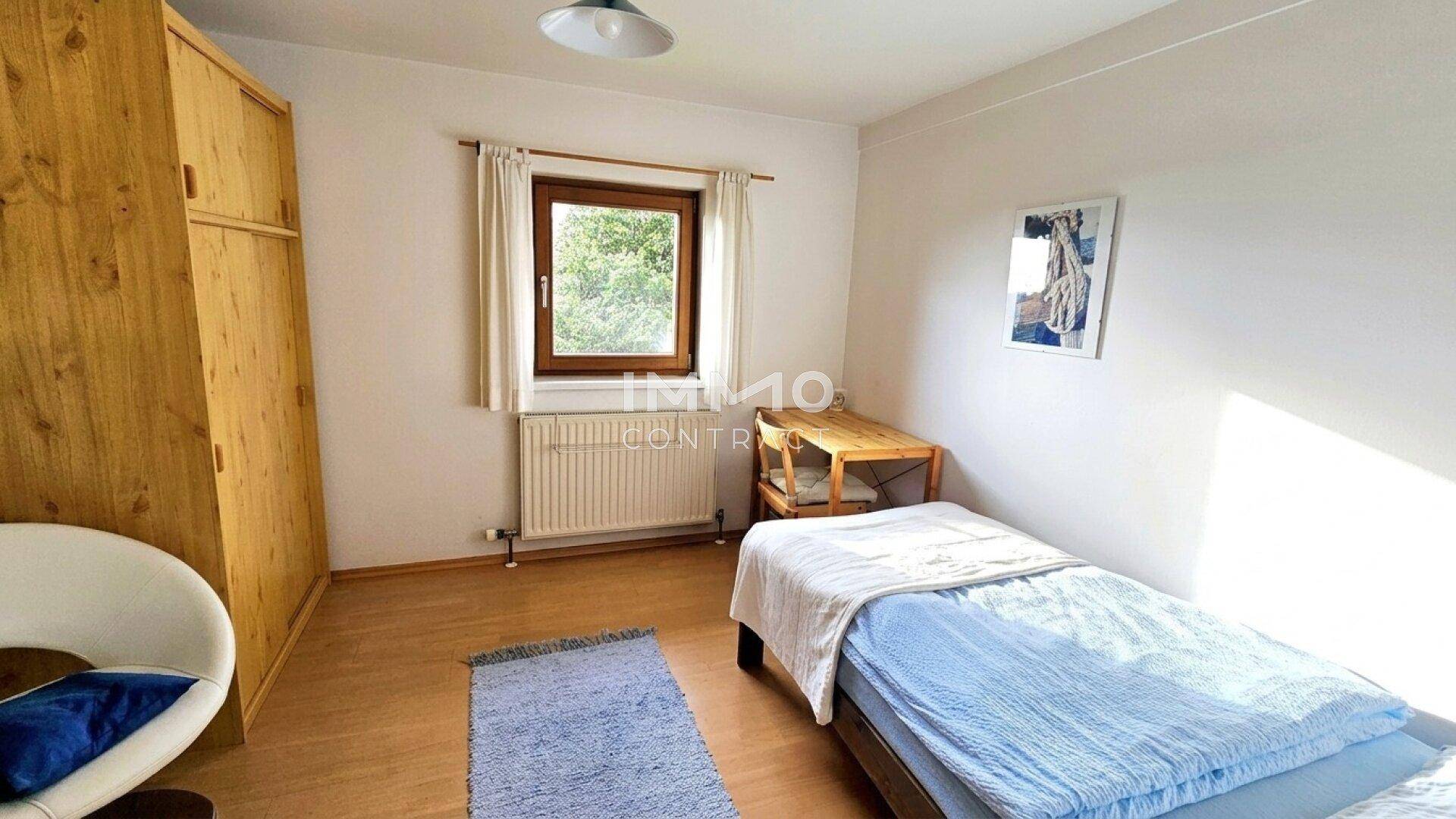 Einfaches Schlafzimmer mit Einzelbett, Holzschrank und hellem Laminatboden.