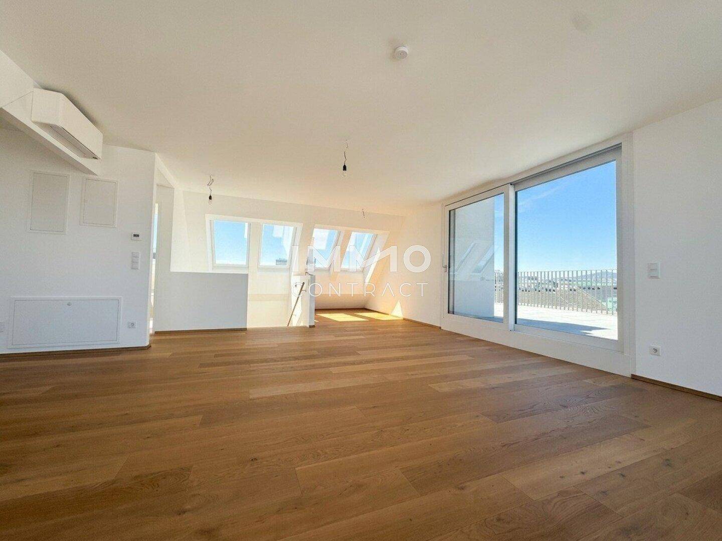 Heller Wohnbereich mit Holzboden, großen Fenstern und Zugang zur Terrasse.