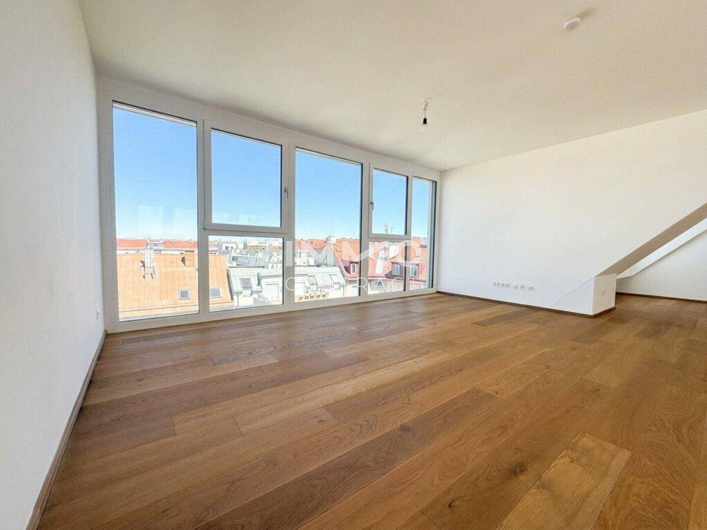 Lichtdurchfluteter Wohnraum mit Holzboden und Panoramafenstern mit Stadtblick.