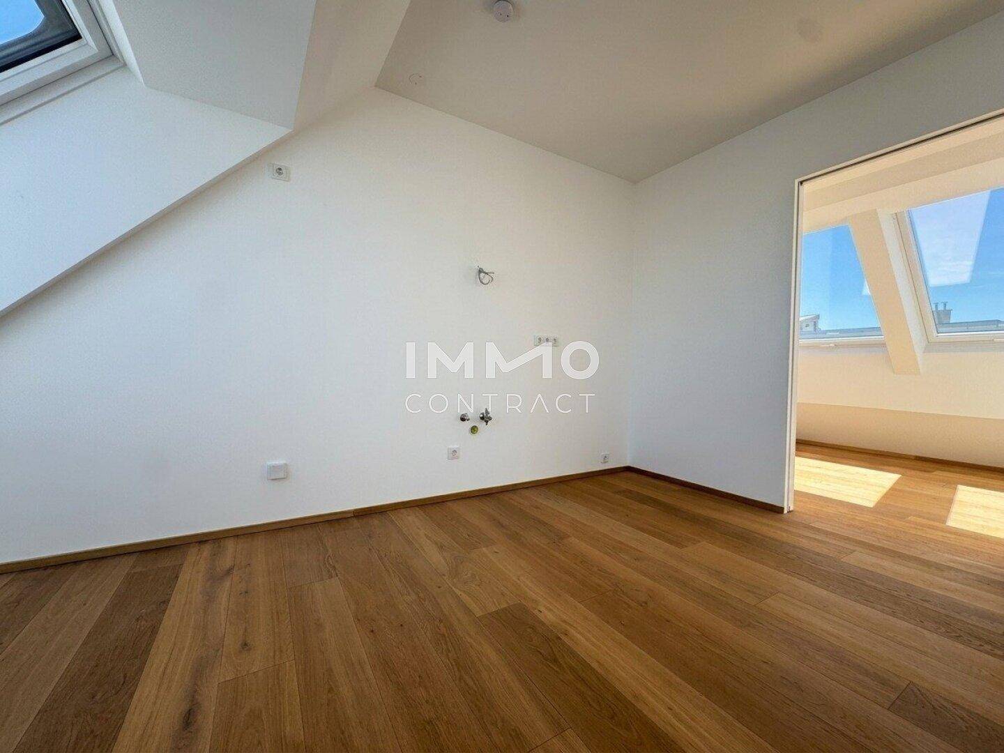 Schlafzimmer mit Holzboden, weißen Wänden und Dachfenstern für viel Tageslicht.
