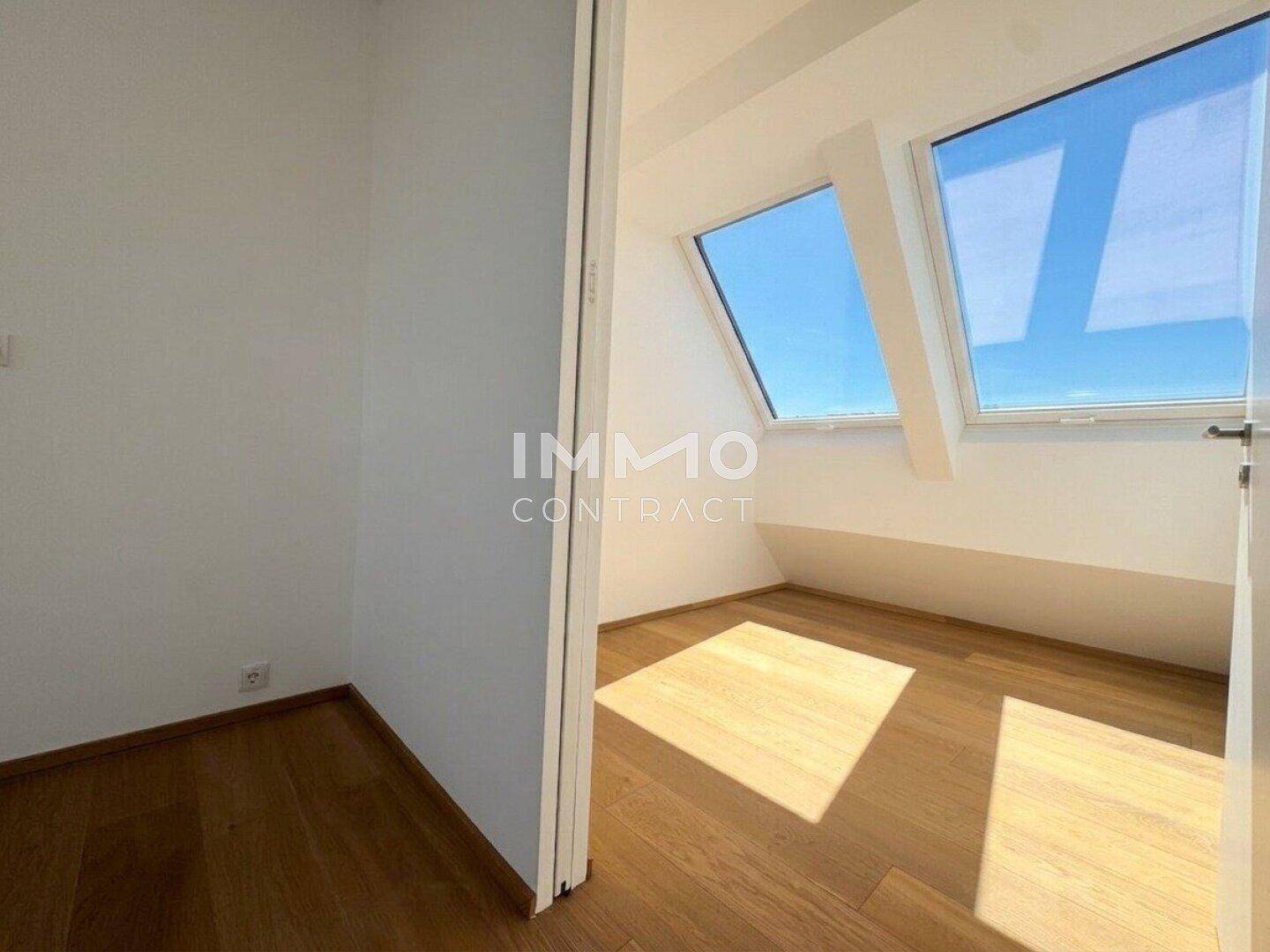 Schlafzimmer mit Holzboden, weißen Wänden und schrägen Dachfenstern.