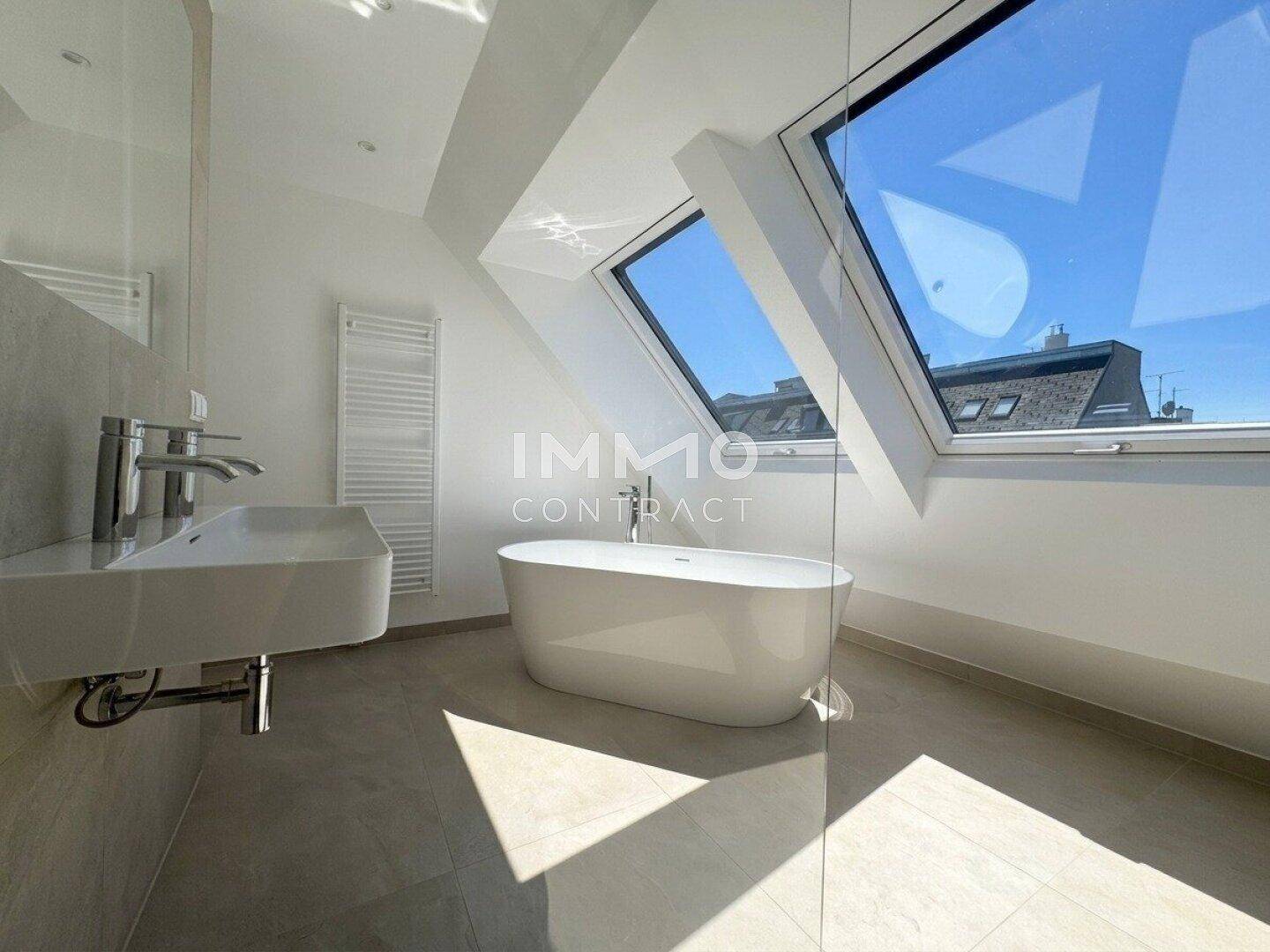 Elegantes Badezimmer mit freistehender Badewanne, Waschtisch und Dachfenstern.