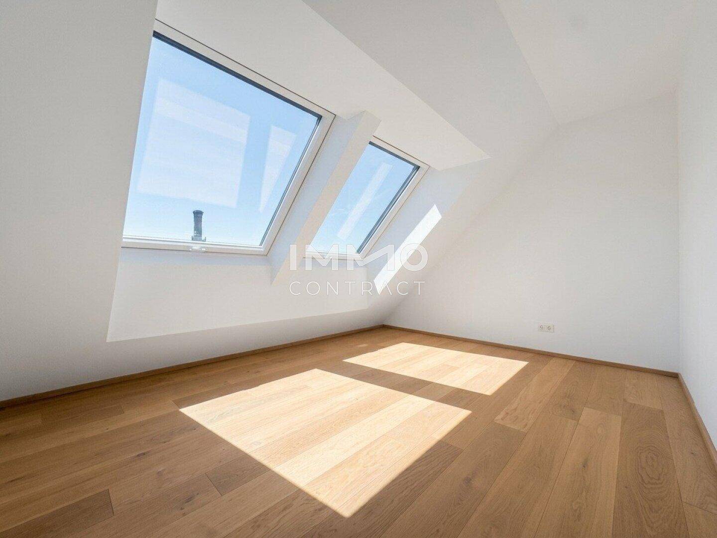 Schlafzimmer mit Holzboden, weißen Wänden und schrägen Dachfenstern.
