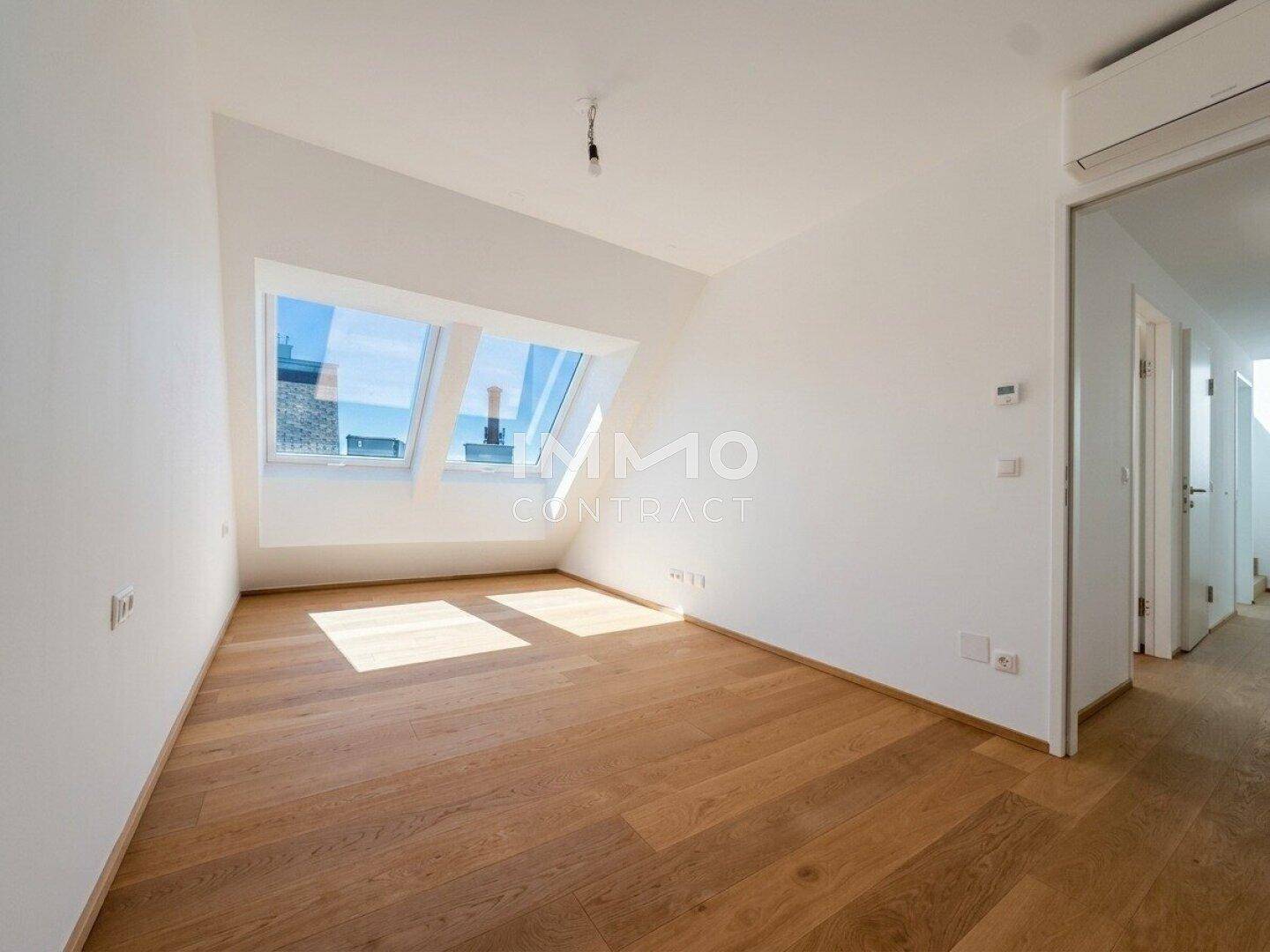 Helles Schlafzimmer mit Holzboden, Klimaanlage und Dachfenstern.